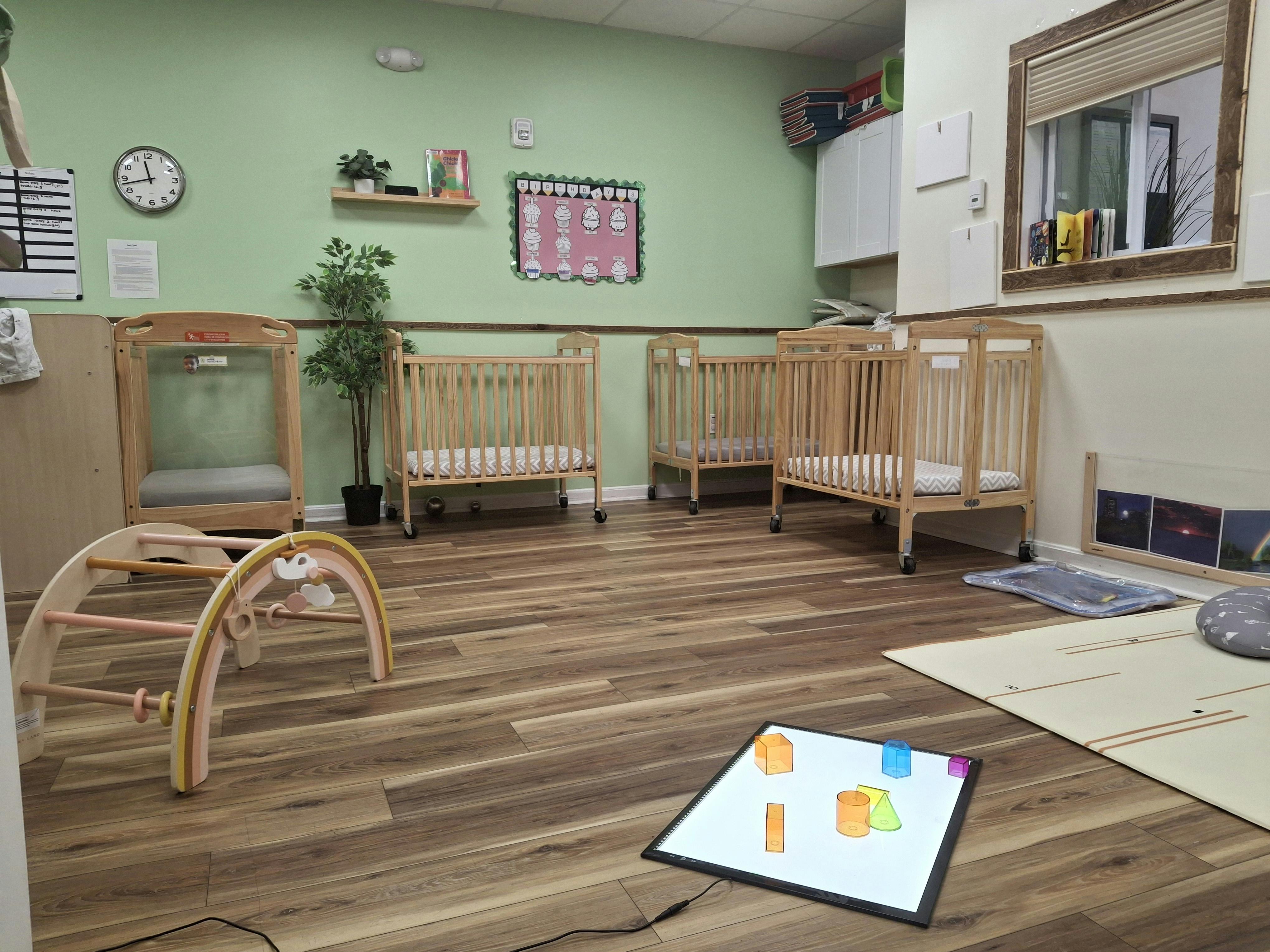 Room with multiple cribs and play equipment