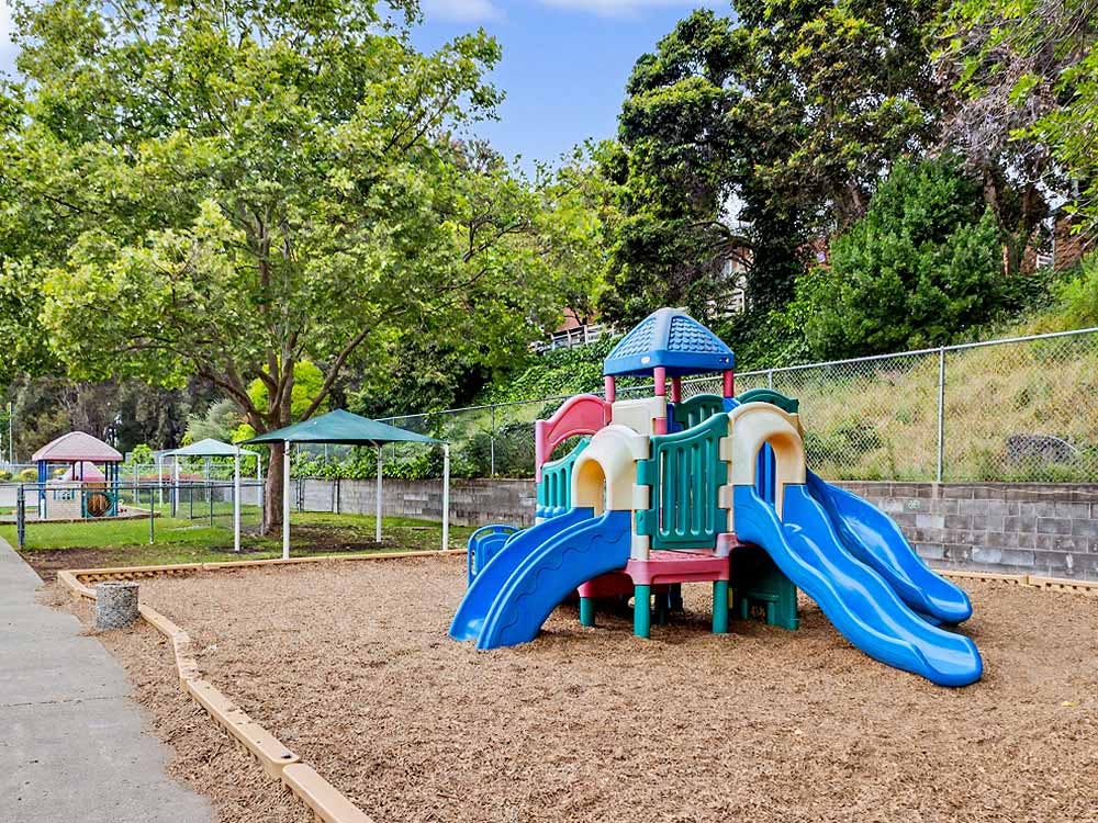 A colorful playground structure with slides on a wood chip ground