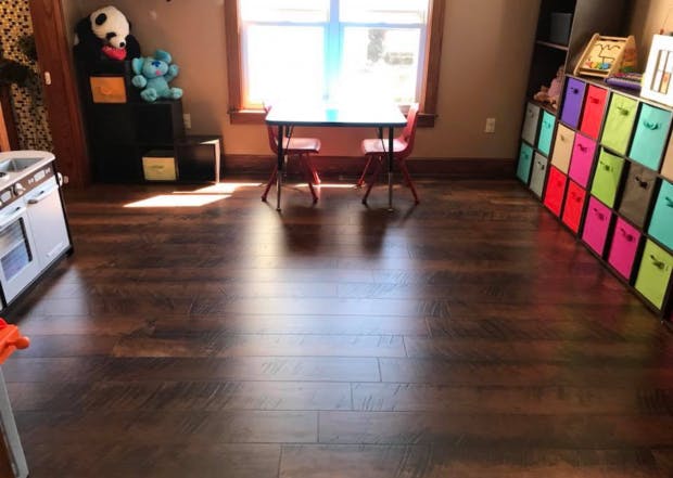 Room with dark wood floor, small table and chairs, and colorful storage bins