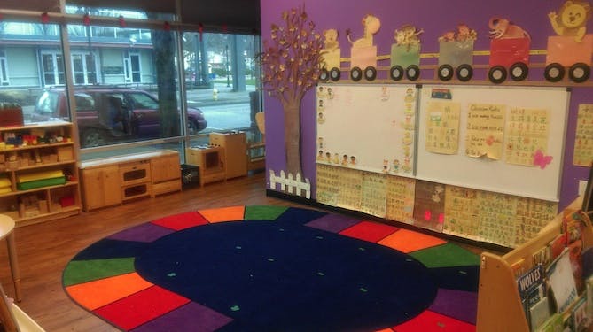 Classroom with colorful rug, whiteboards, and window