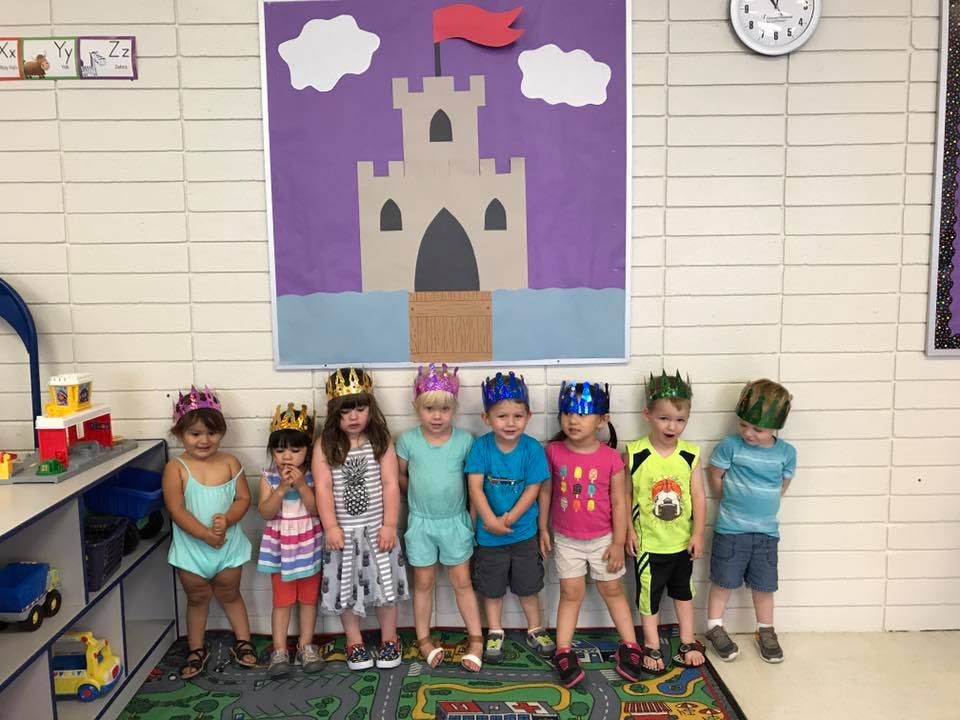 Seven children wearing crowns standing in a line