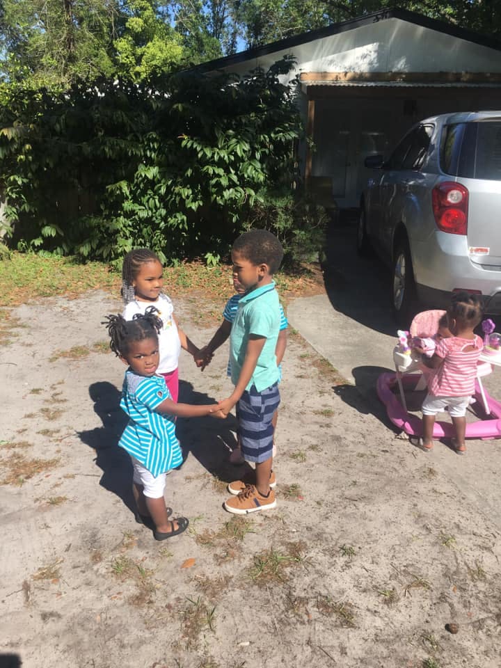 Four children holding hands in a circle outdoors
