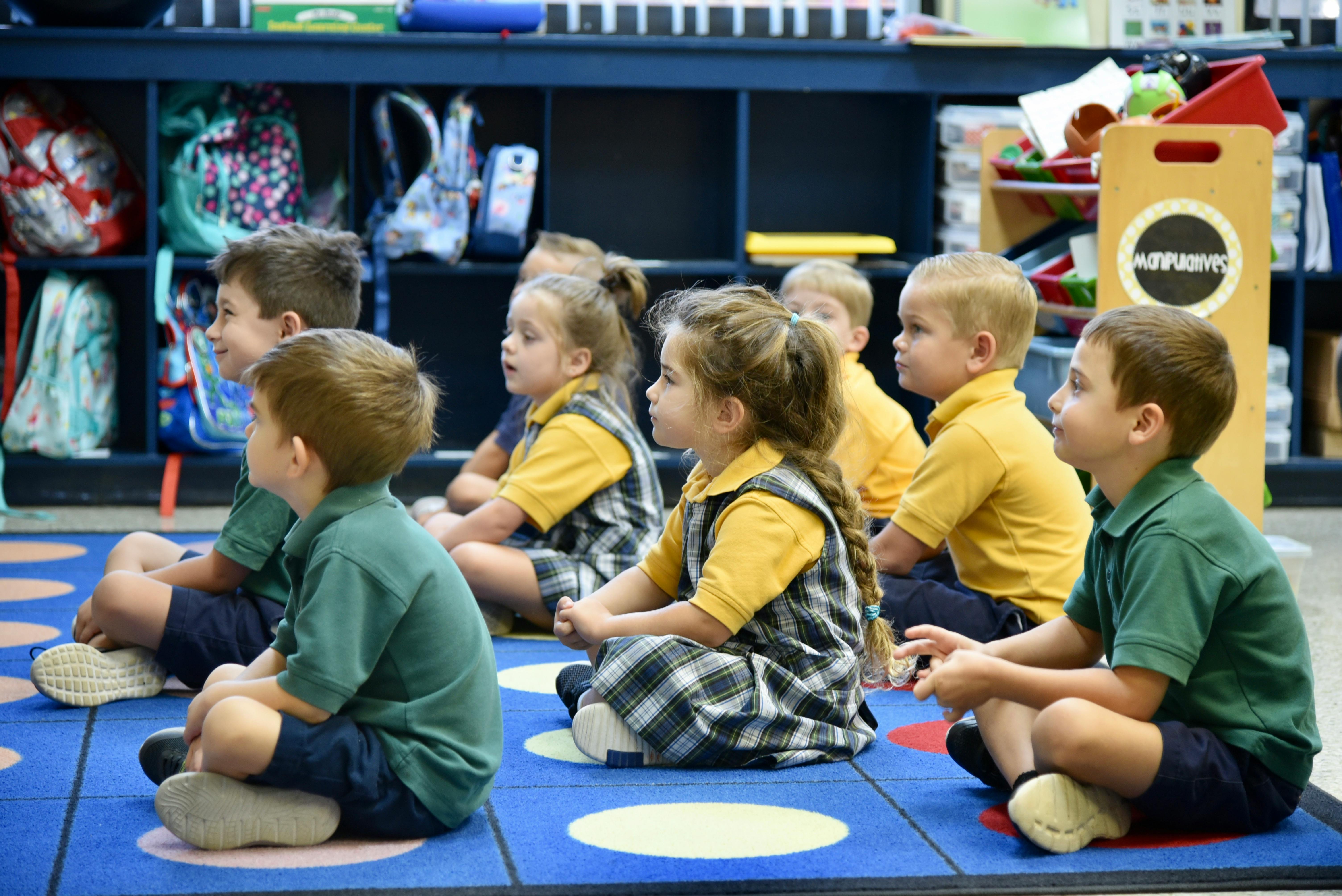 Children sitting on a rug in a classroom