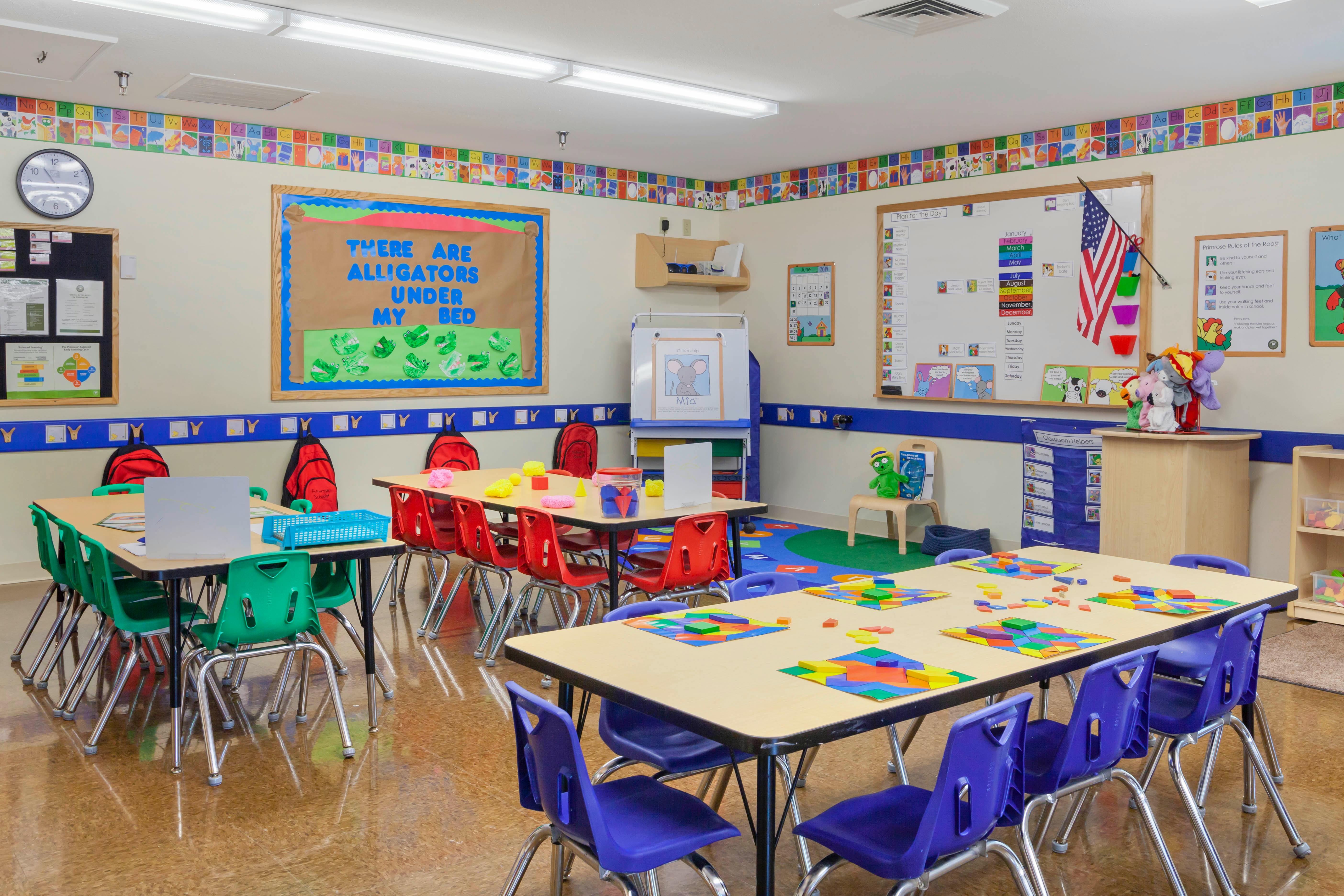 An empty classroom with small tables and colorful chairs arranged in groups