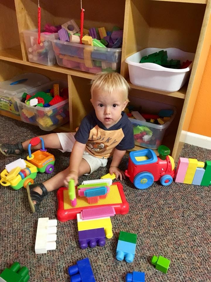 Child sitting on floor playing with colorful toys