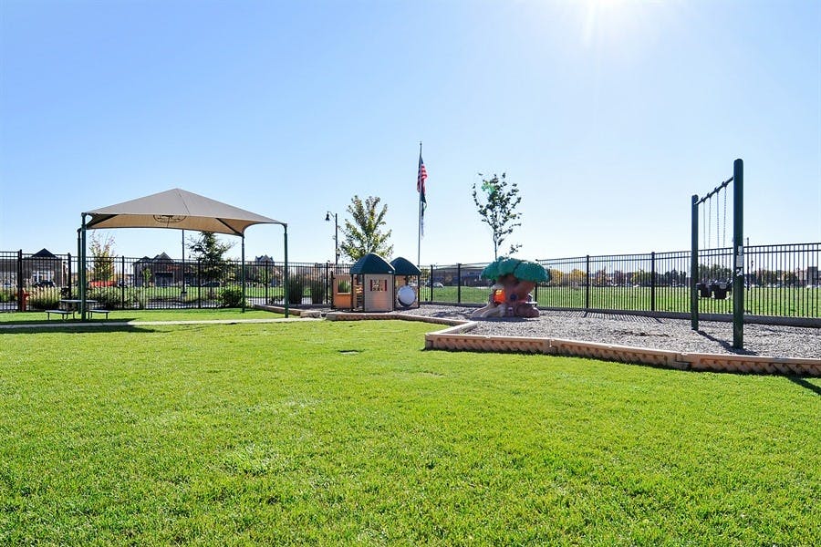 Grassy area with a playground, swing set, and shaded seating