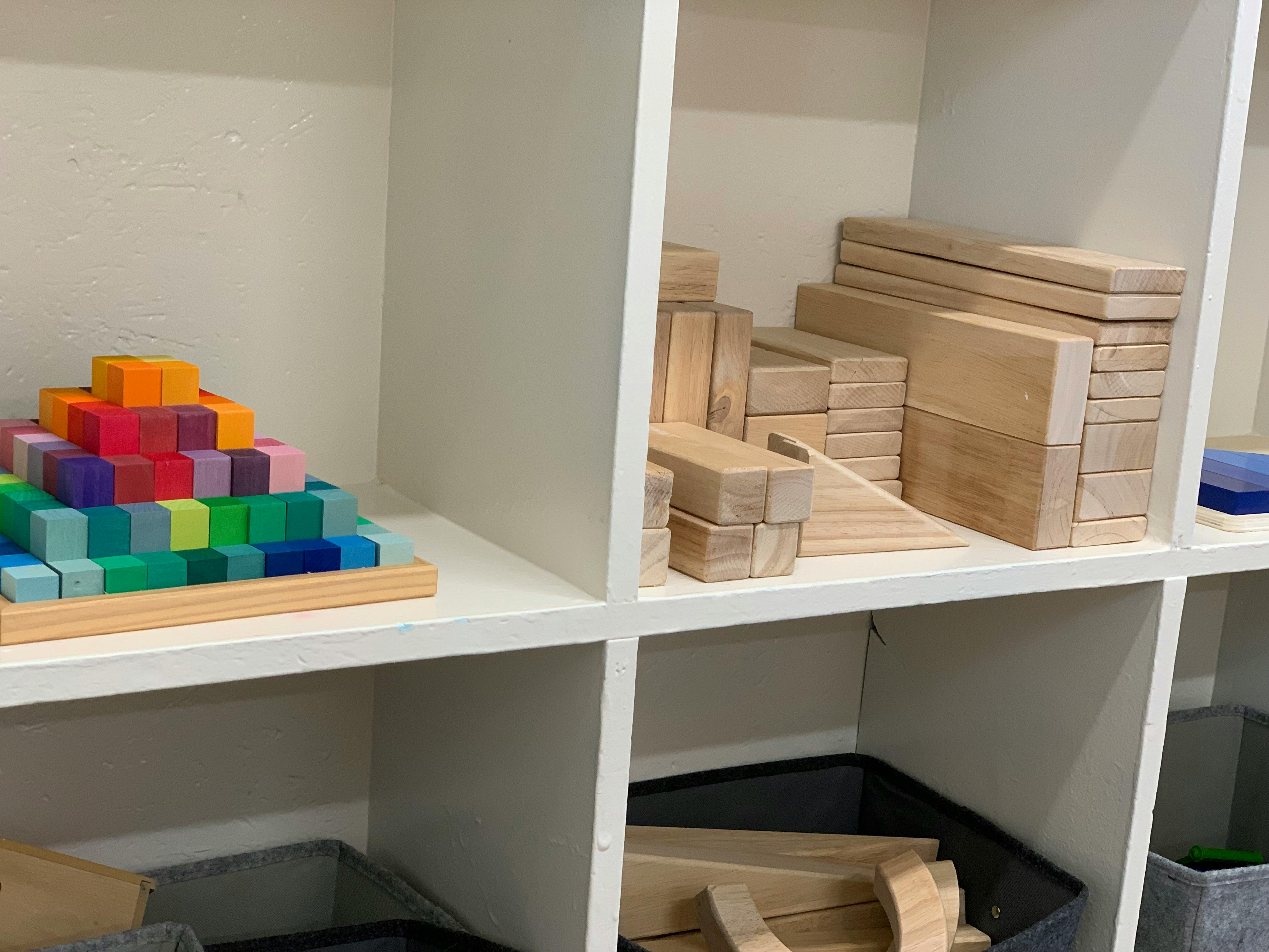 Colorful blocks stacked in a pyramid shape next to wooden blocks on shelves
