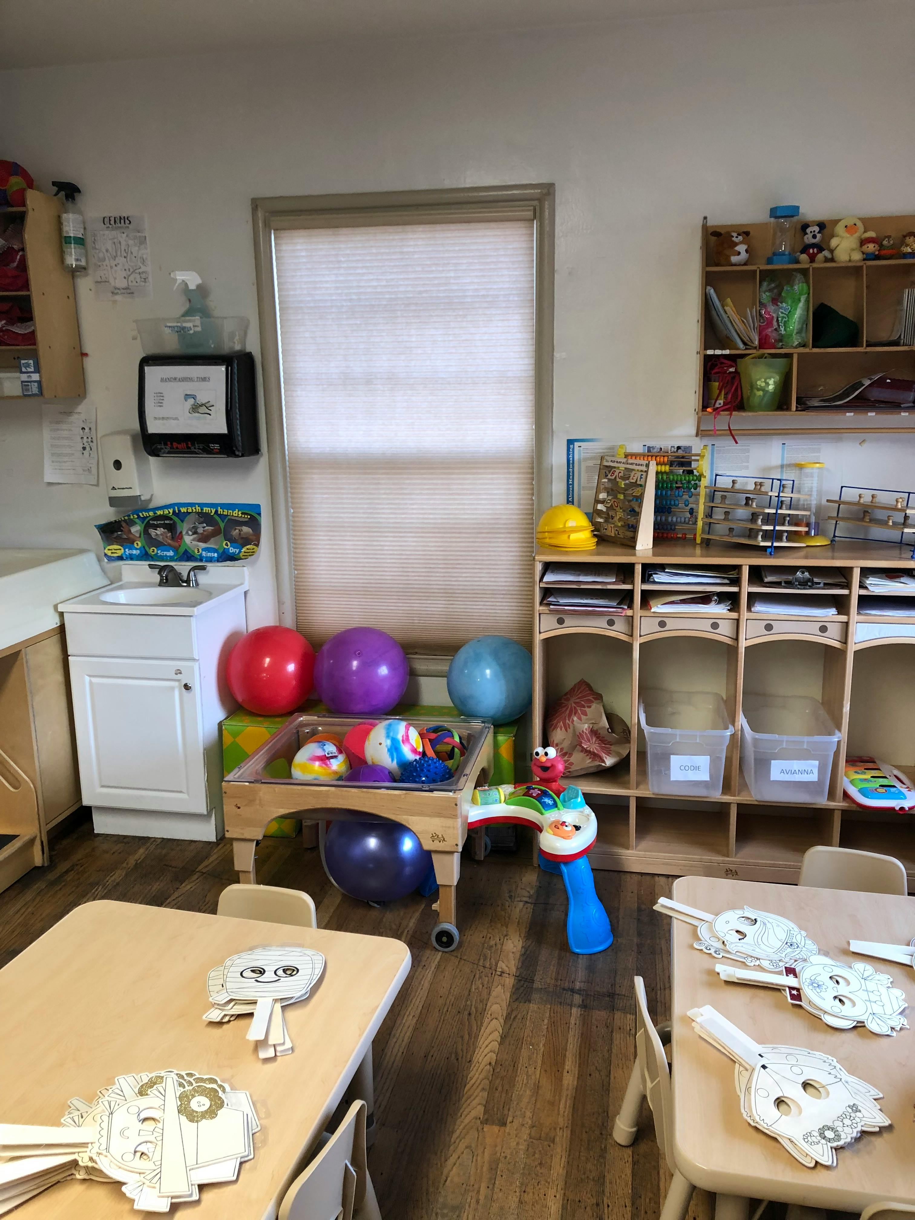 Classroom with small tables, chairs, toys, and storage shelves