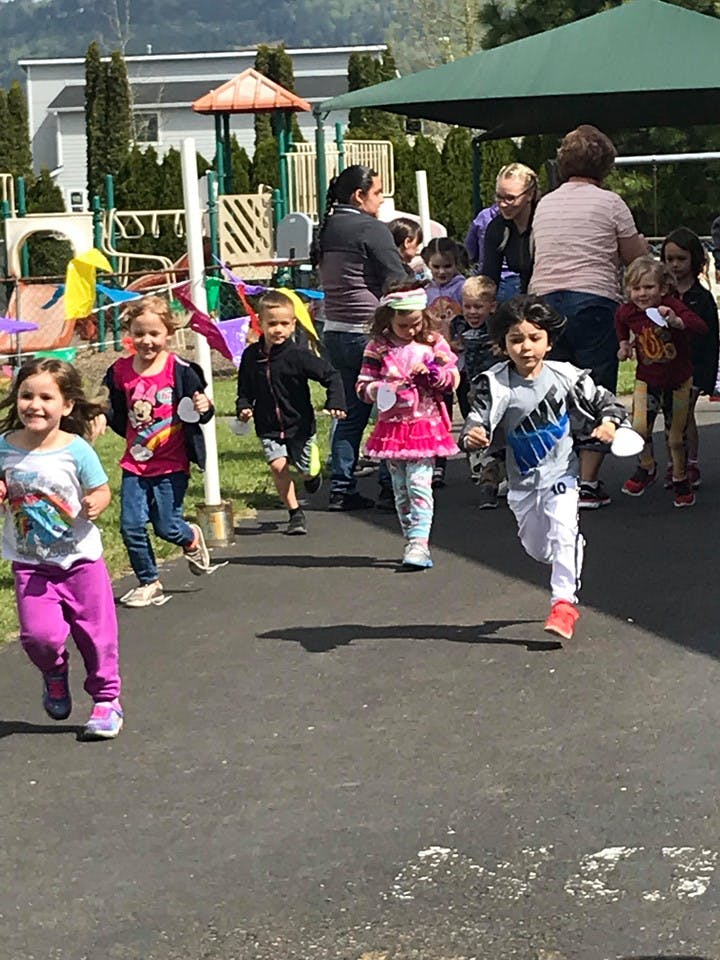 Children running outdoors with adults in the background