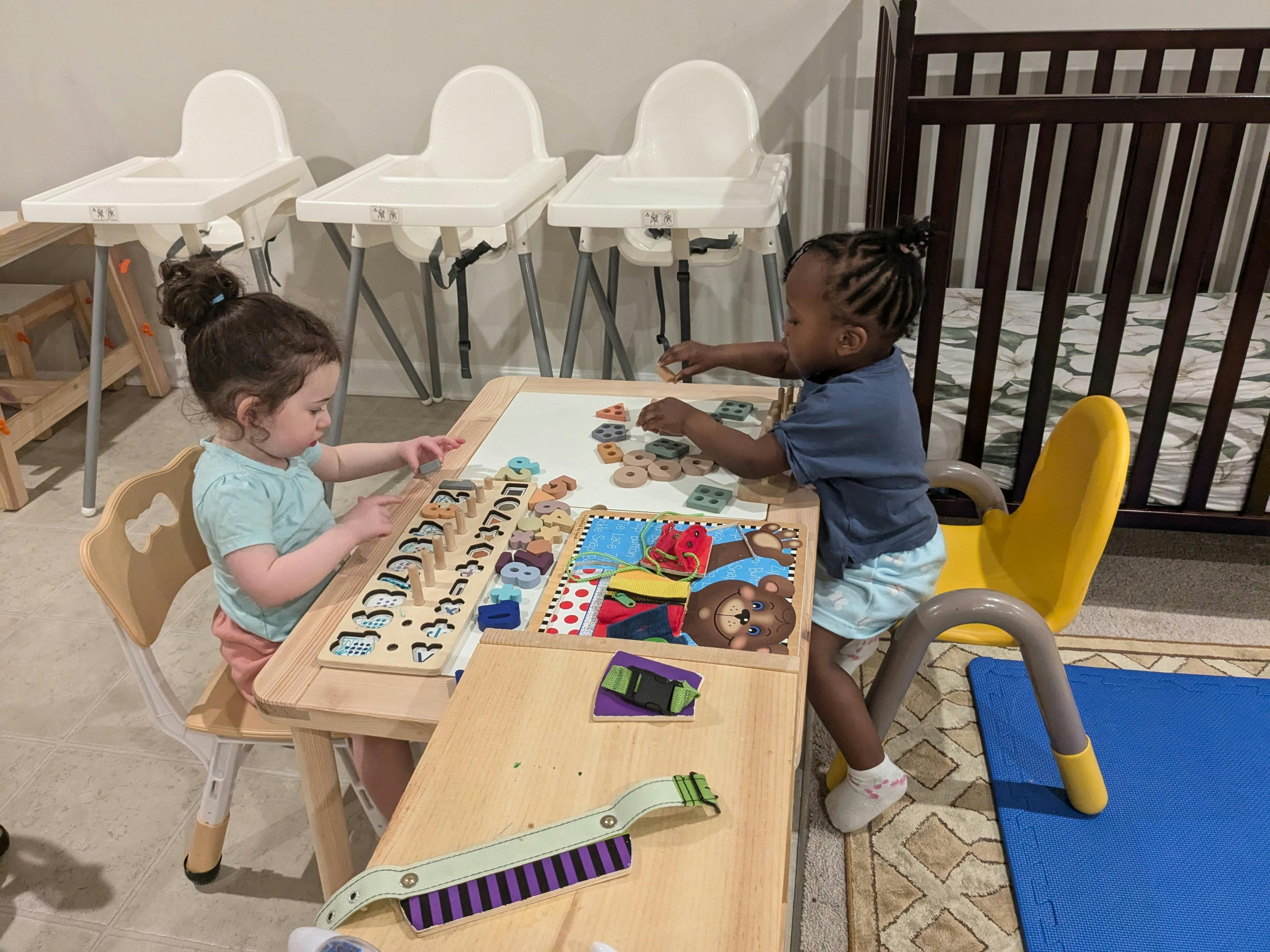 Two children playing with puzzles at a small table