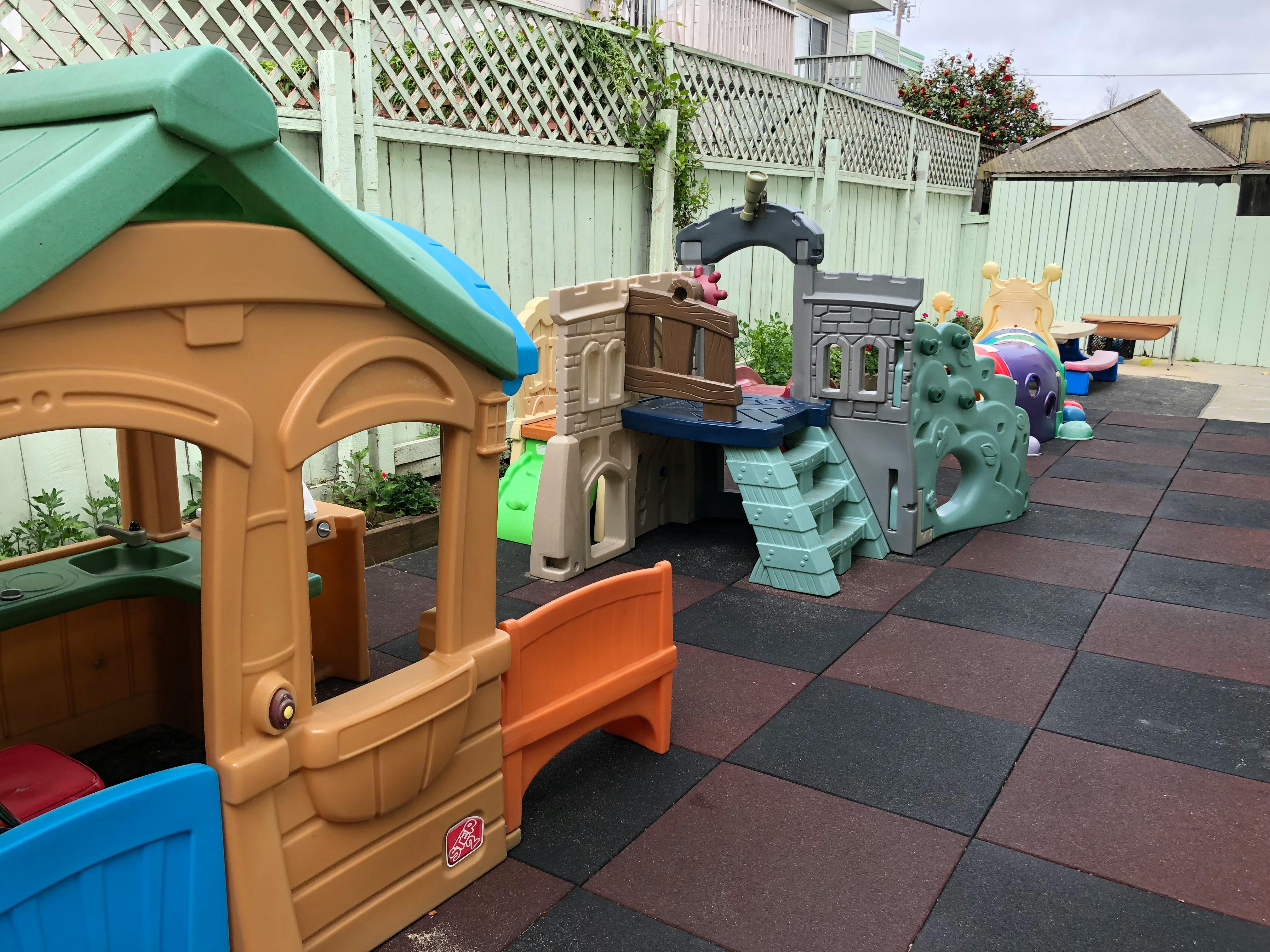 Outdoor playground with playhouses and climbing structures on rubber mats