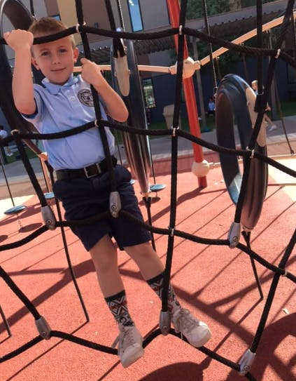 Child climbing on a rope net structure on a playground