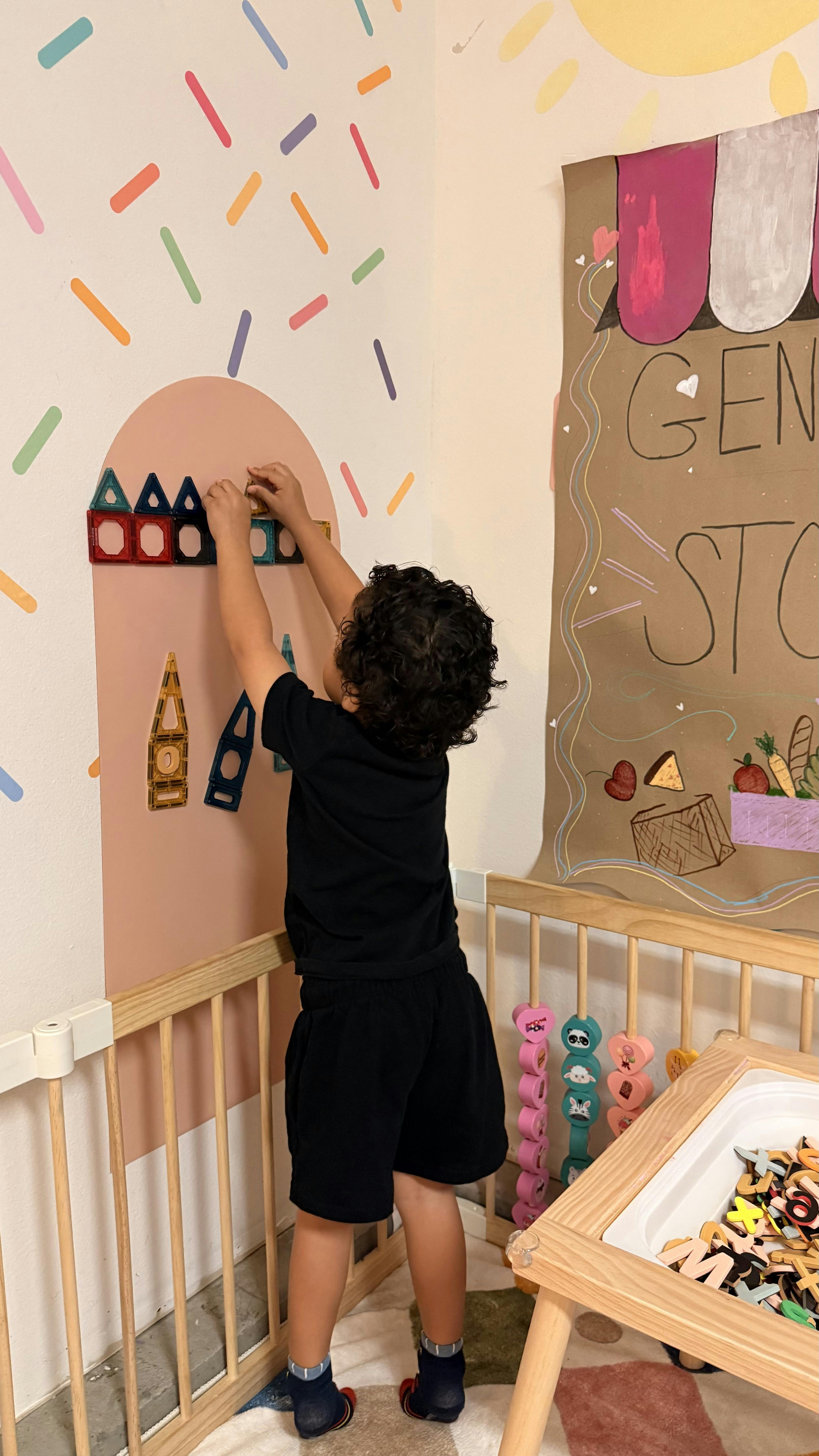 Child building with magnetic shapes on a wall