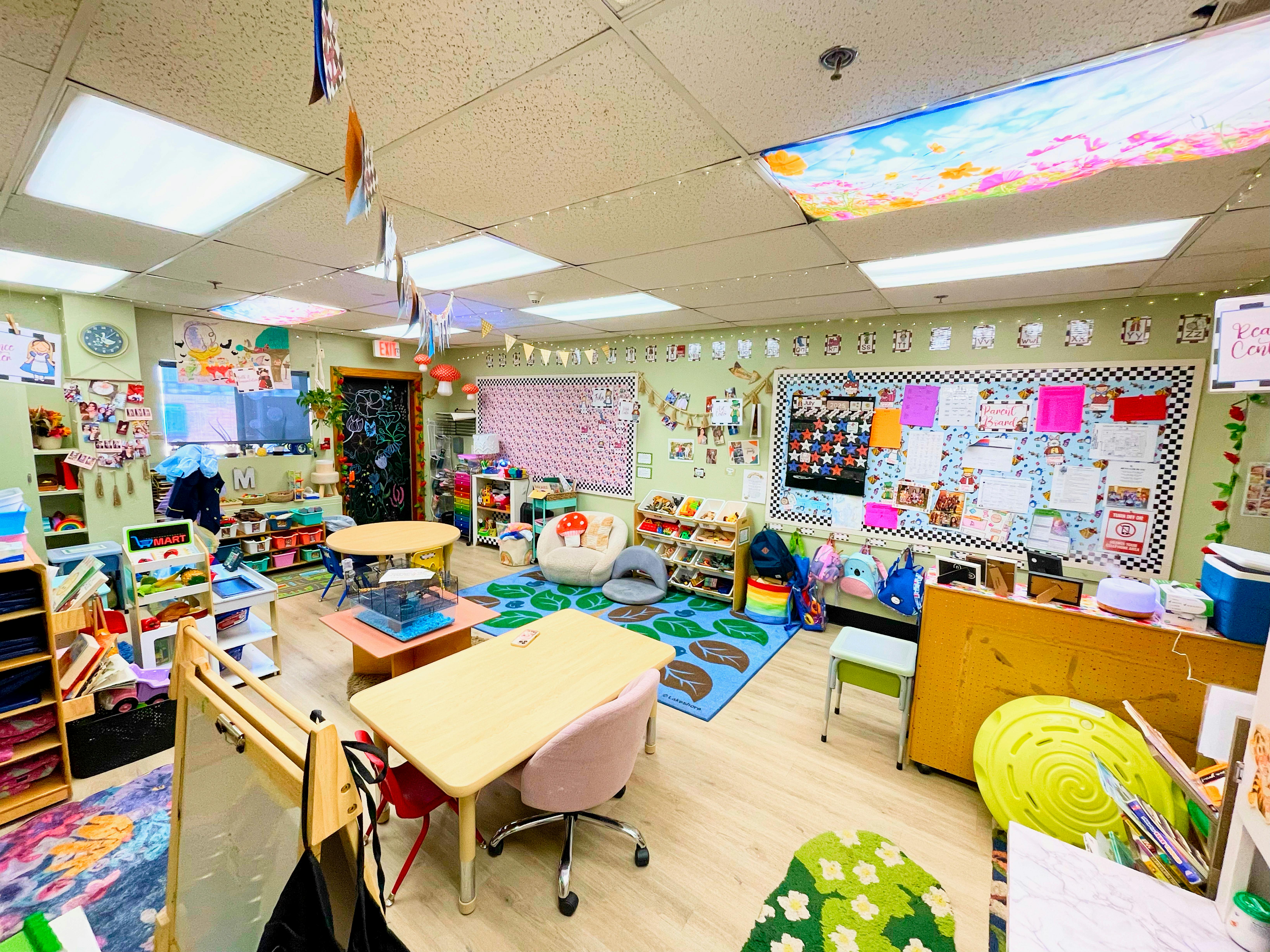 Empty classroom with small tables, chairs, and colorful rugs