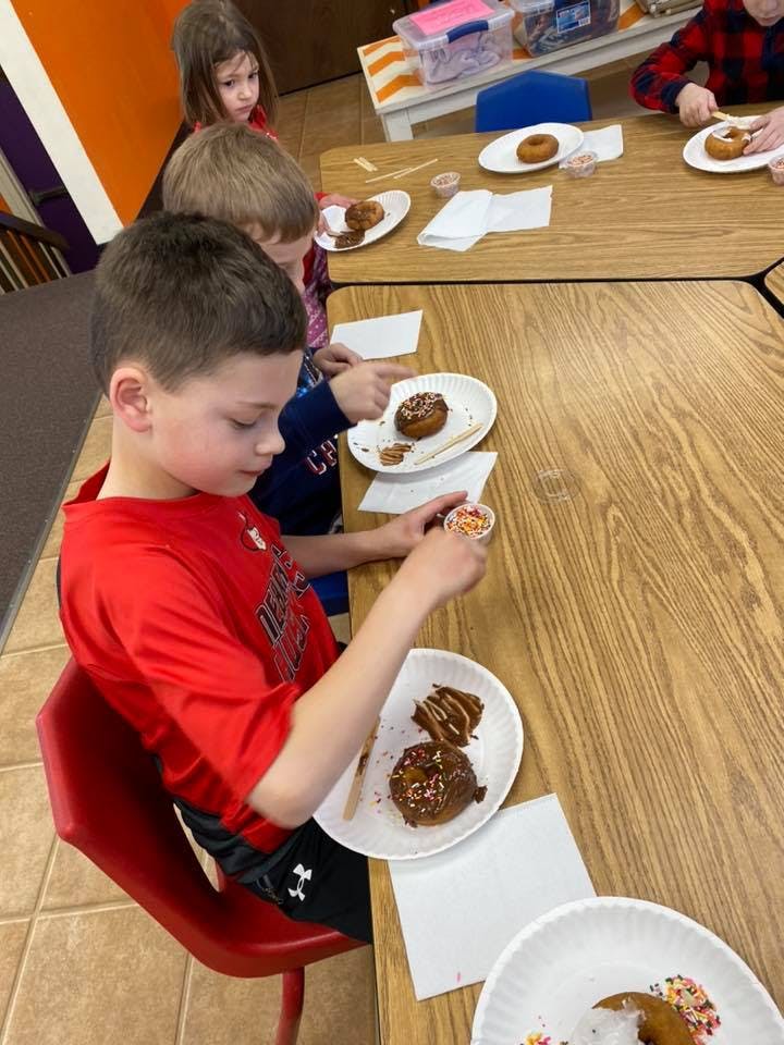 Children decorating donuts at a table