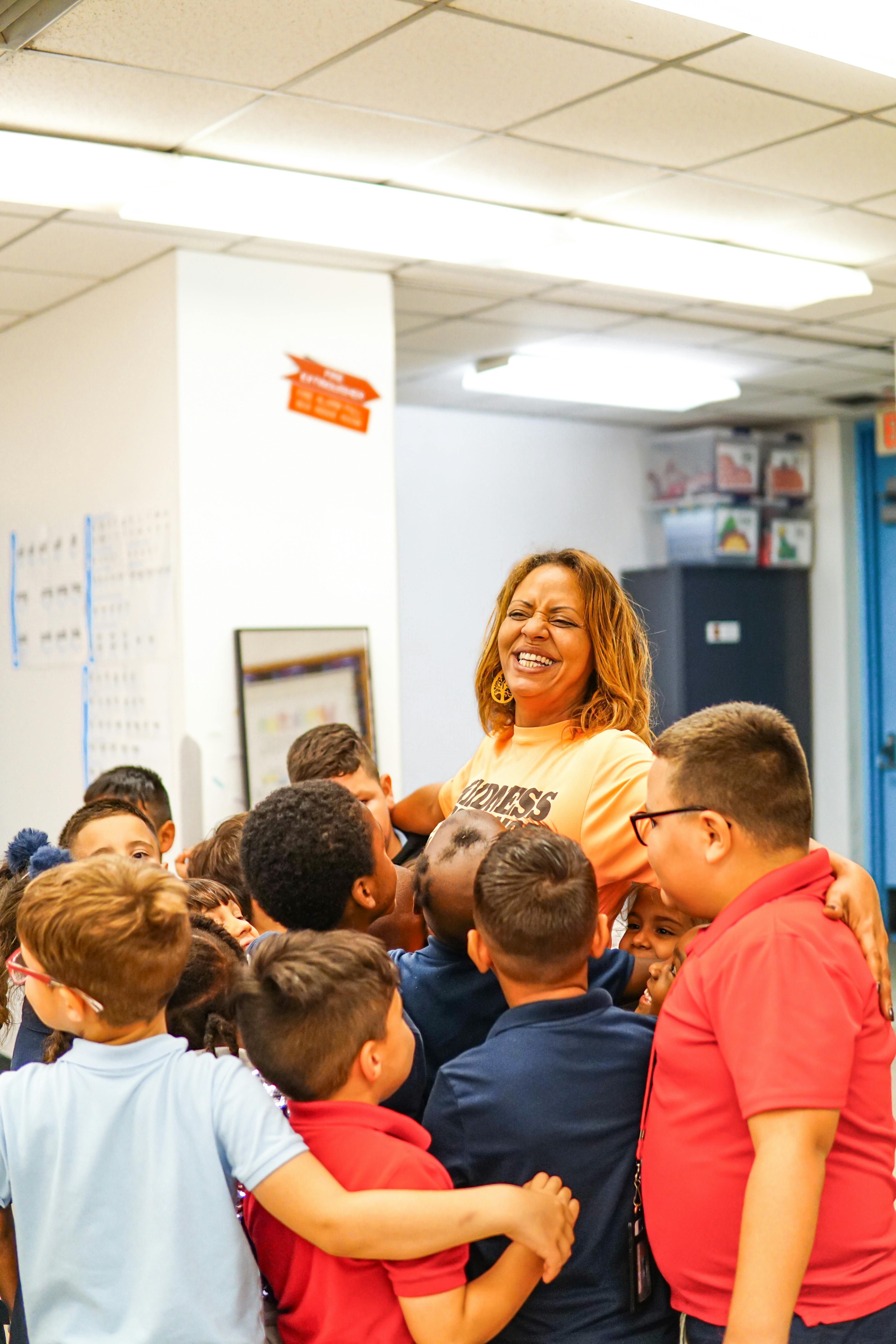 Group of children hugging an adult in a classroom