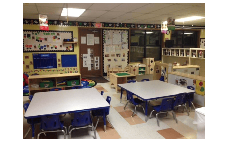 An empty classroom with small tables and chairs