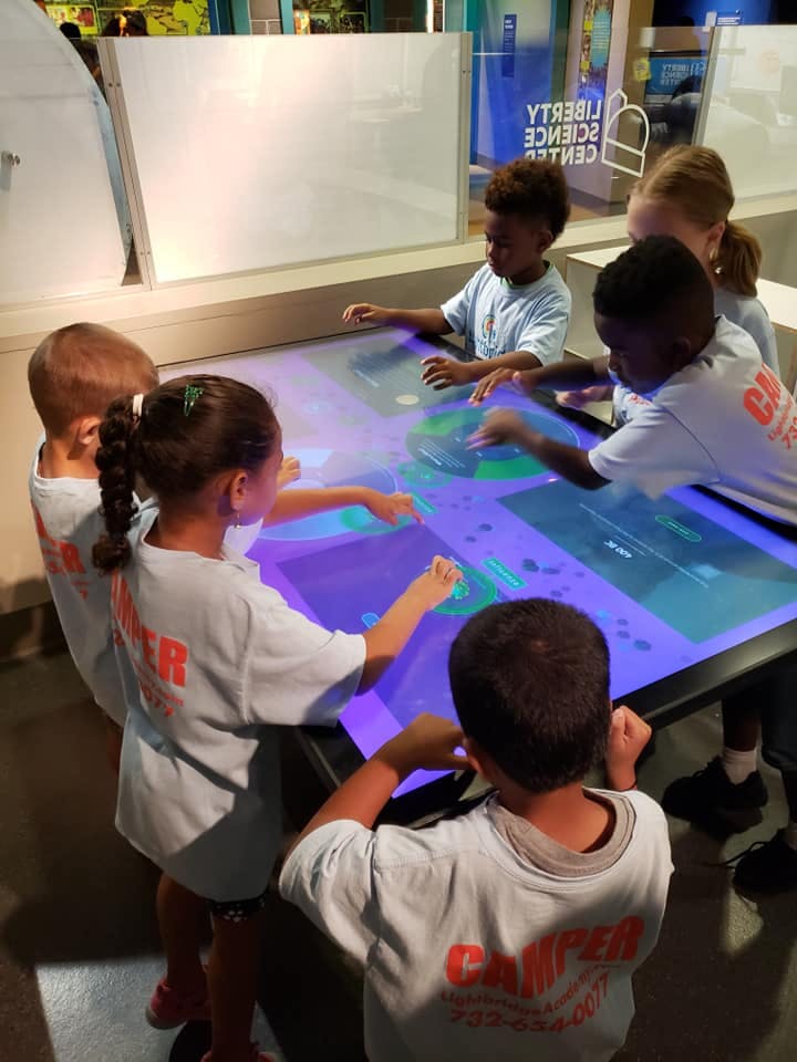 Children interacting with a large glowing touchscreen table