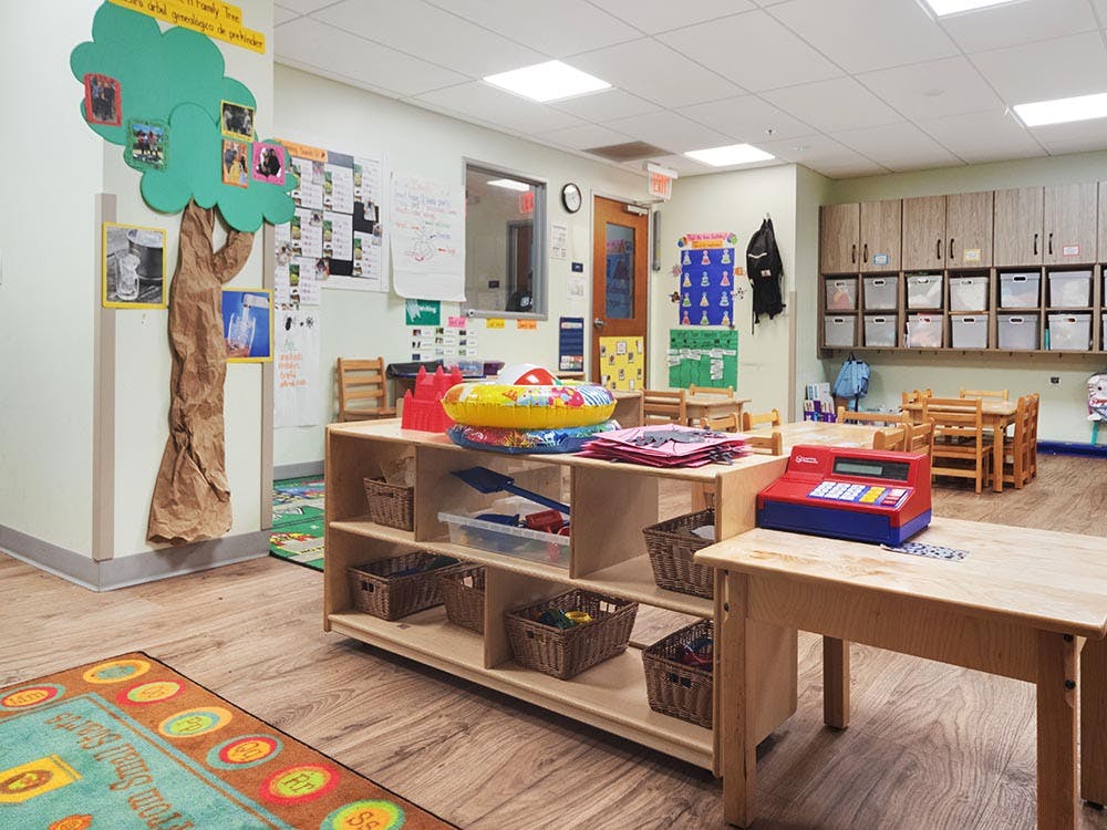 Children's classroom with small wooden tables, shelves, and learning materials