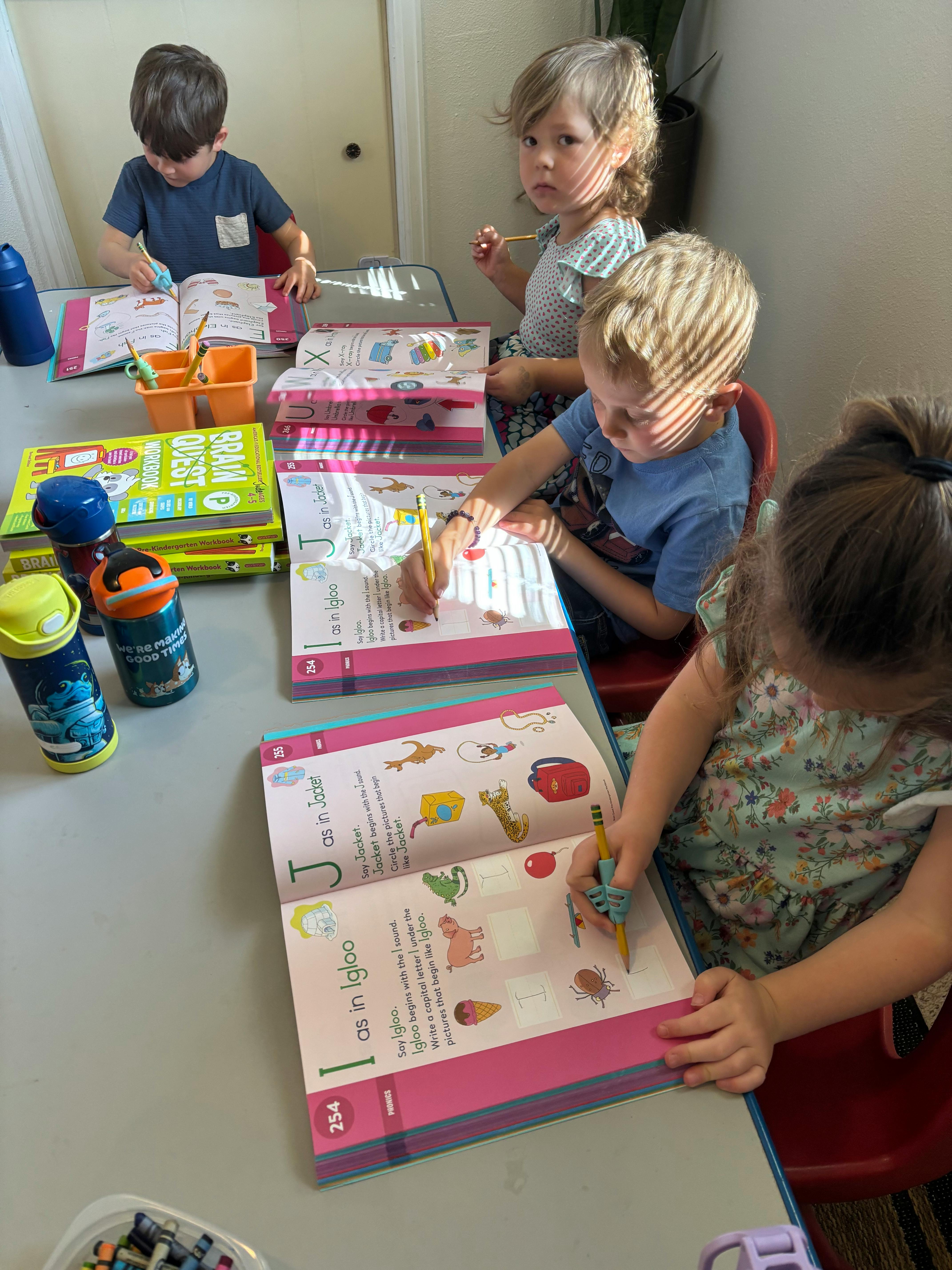 Children sitting at a table with open workbooks