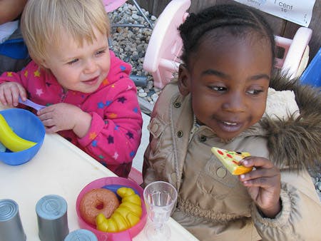 Two children playing with toy food at a table