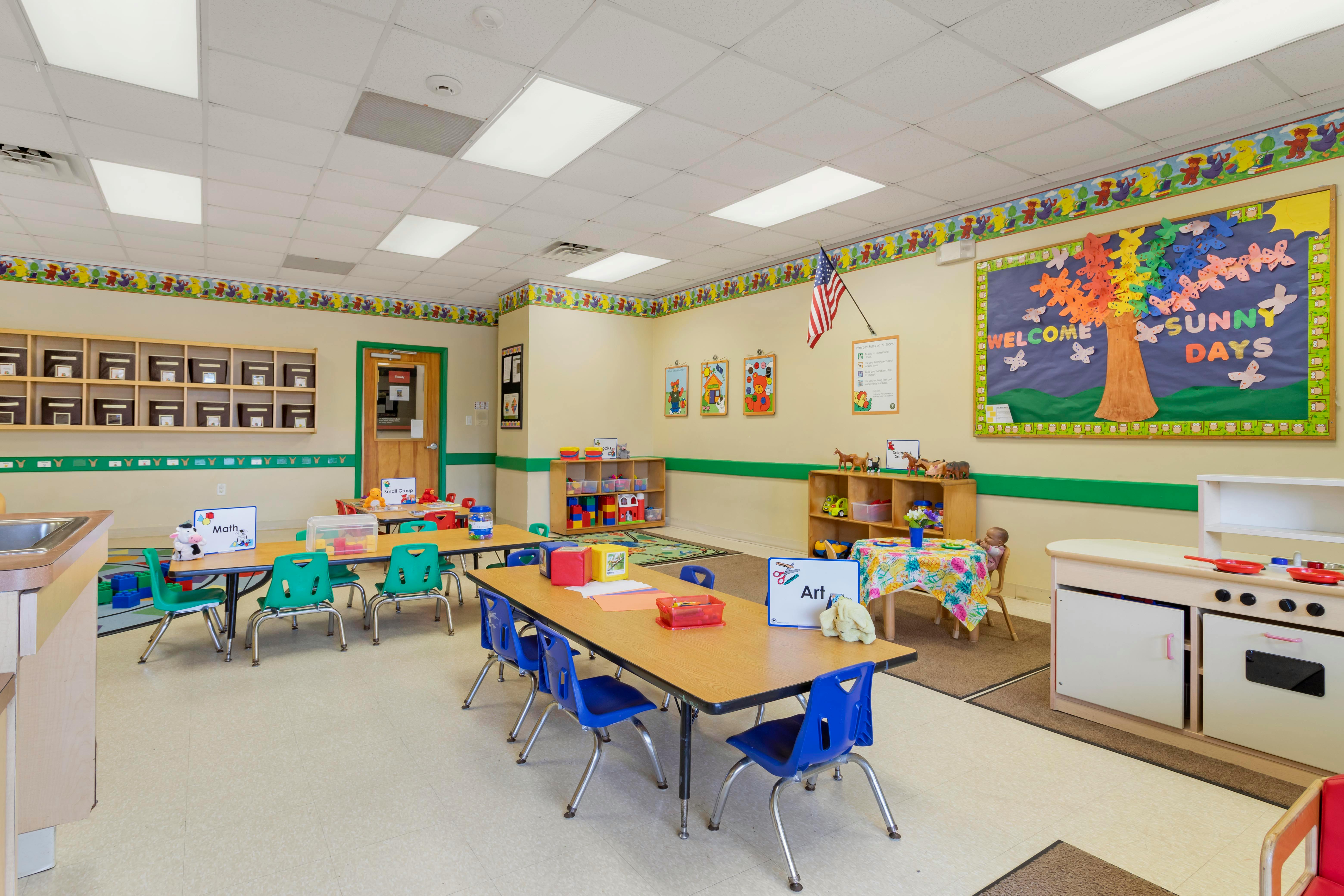 An empty preschool classroom with small tables and chairs