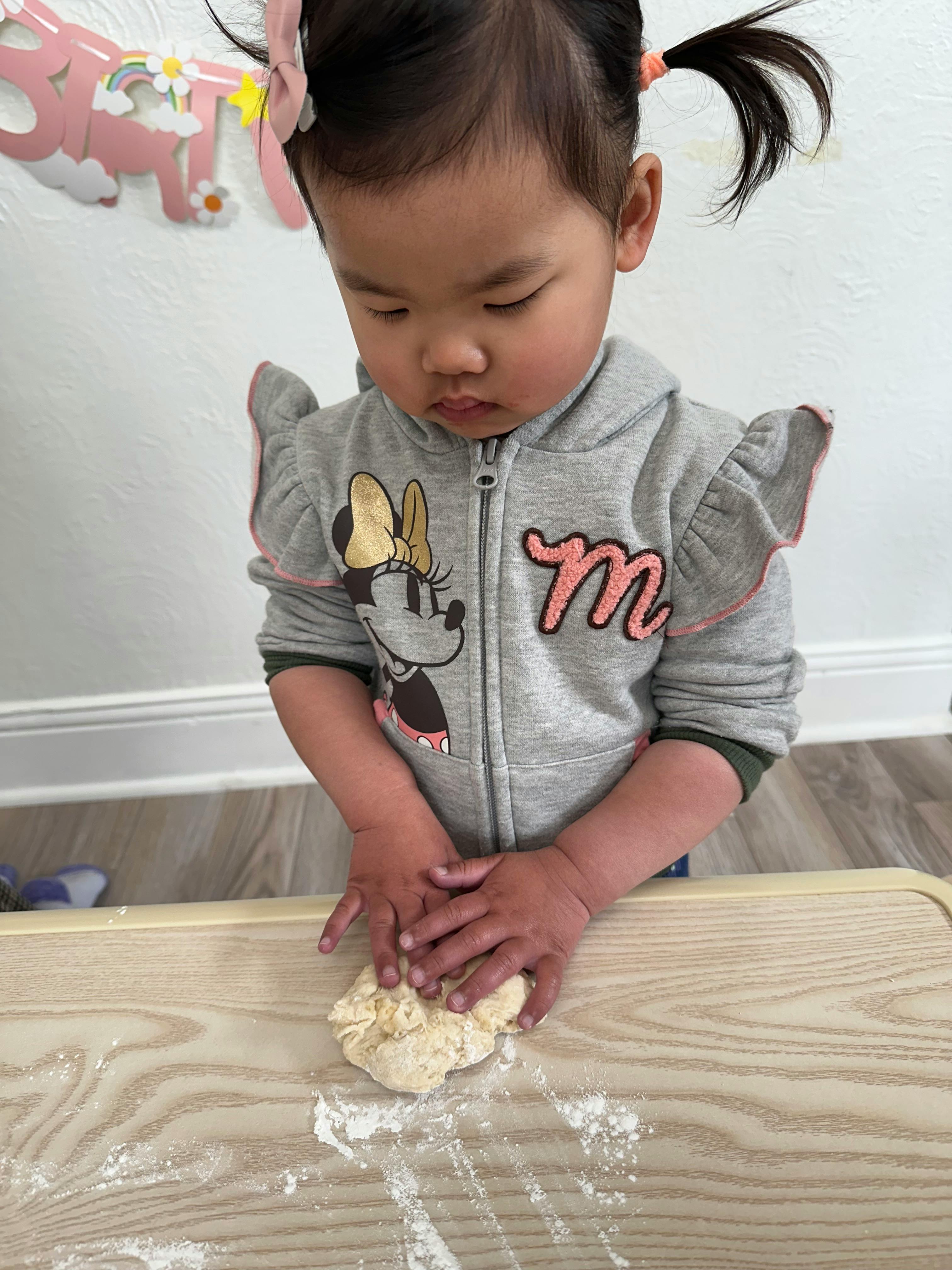 Child kneading dough on a wooden surface