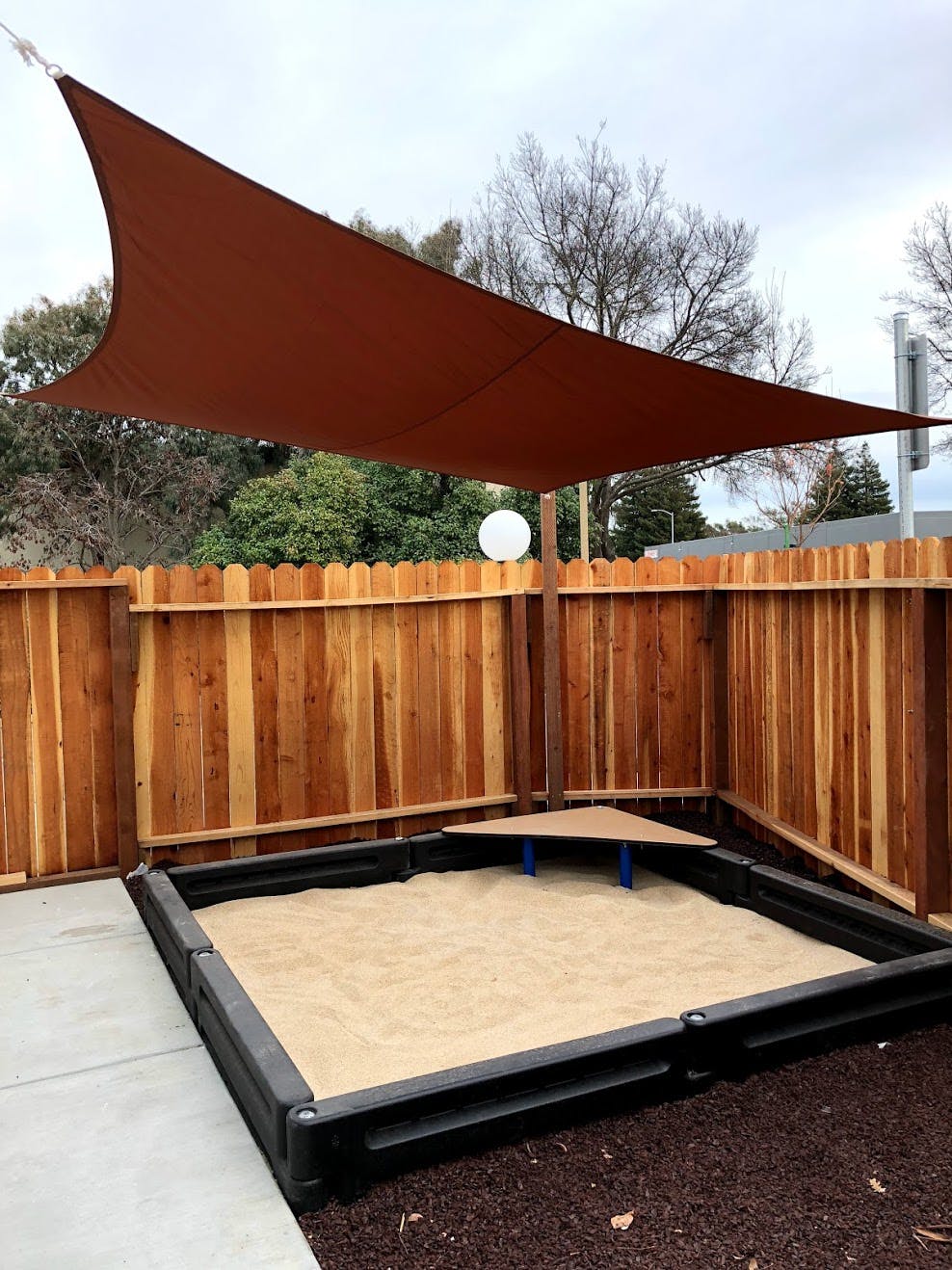 Sandbox with a brown shade sail overhead
