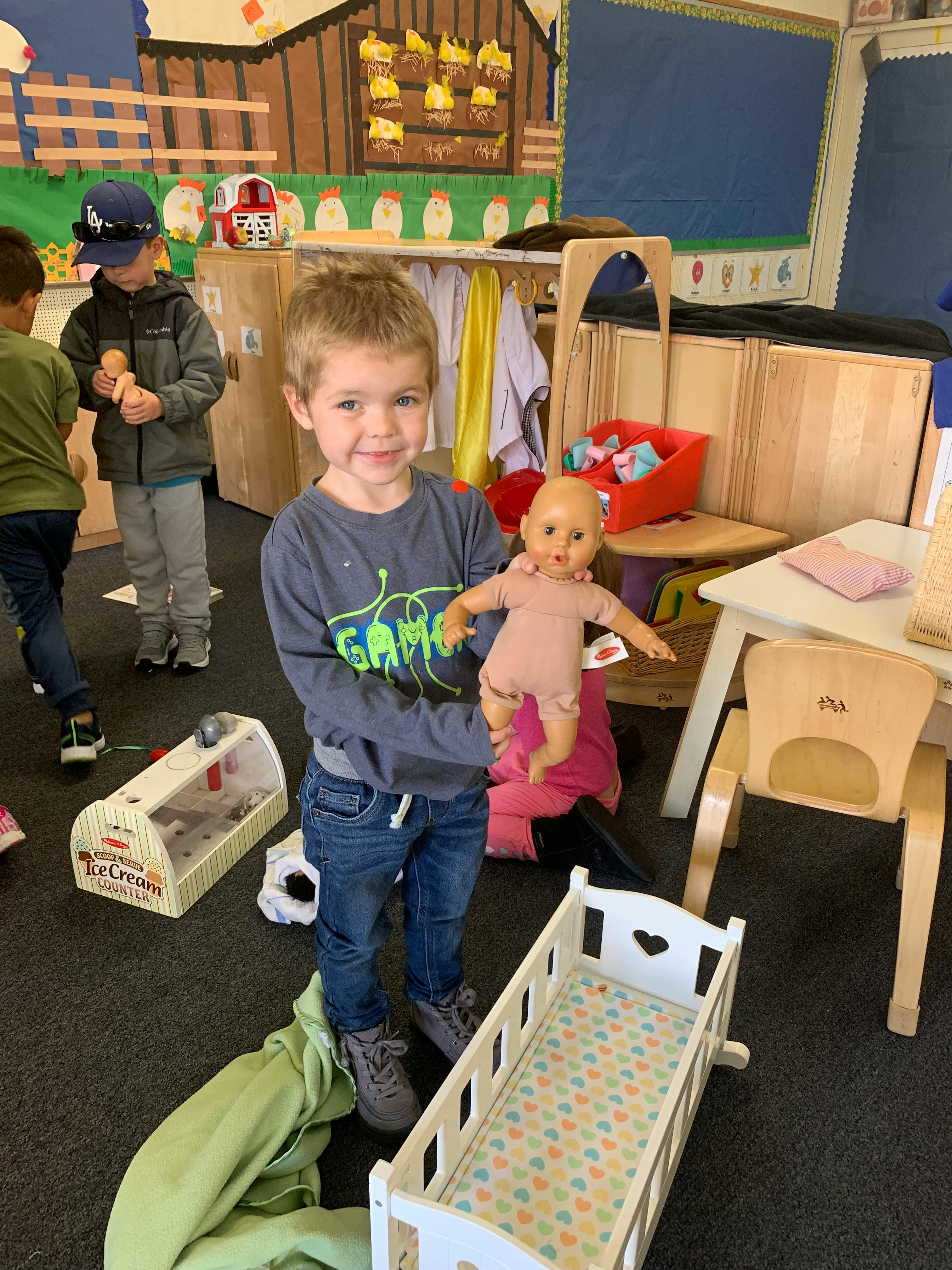 Child holding a doll in a classroom