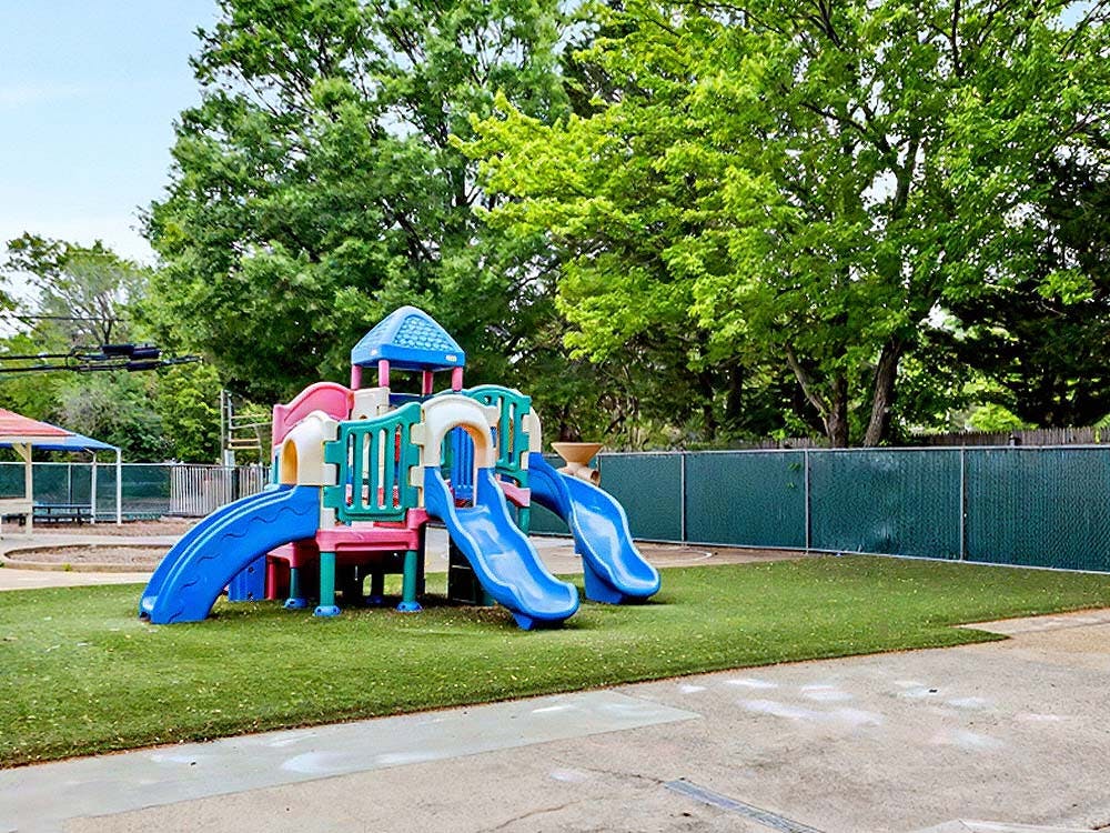 Colorful playground structure with multiple slides on green artificial turf