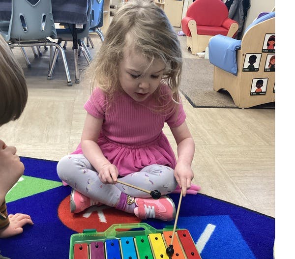 Child playing a xylophone on a rug