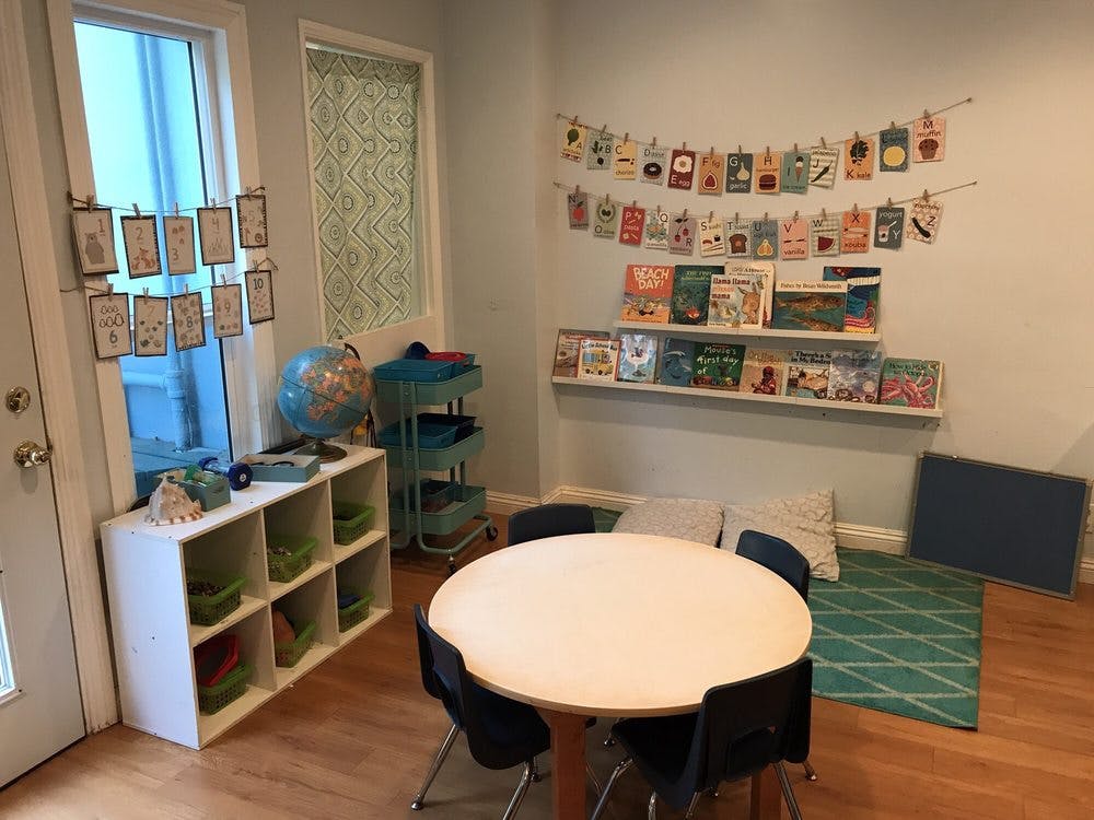 Classroom with small table and chairs, bookshelves, and window decorations