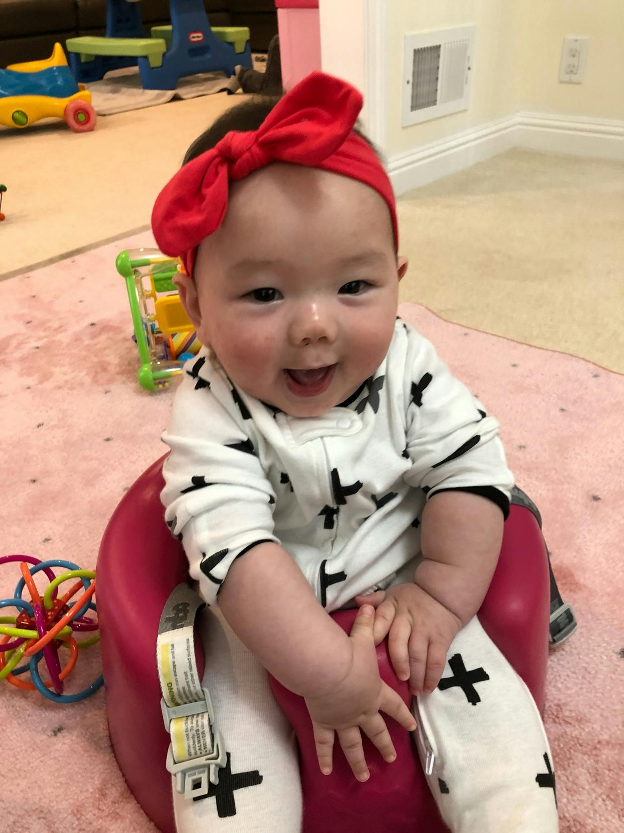 Child in a red headband sitting in a booster seat