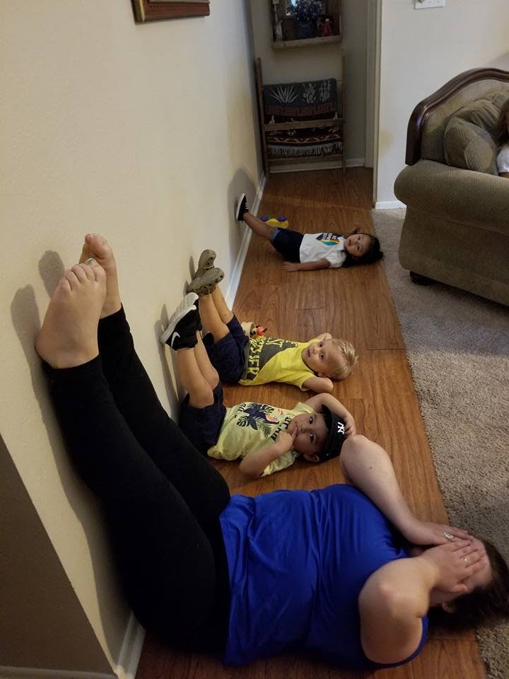 Person and three children lying on the floor with feet against the wall
