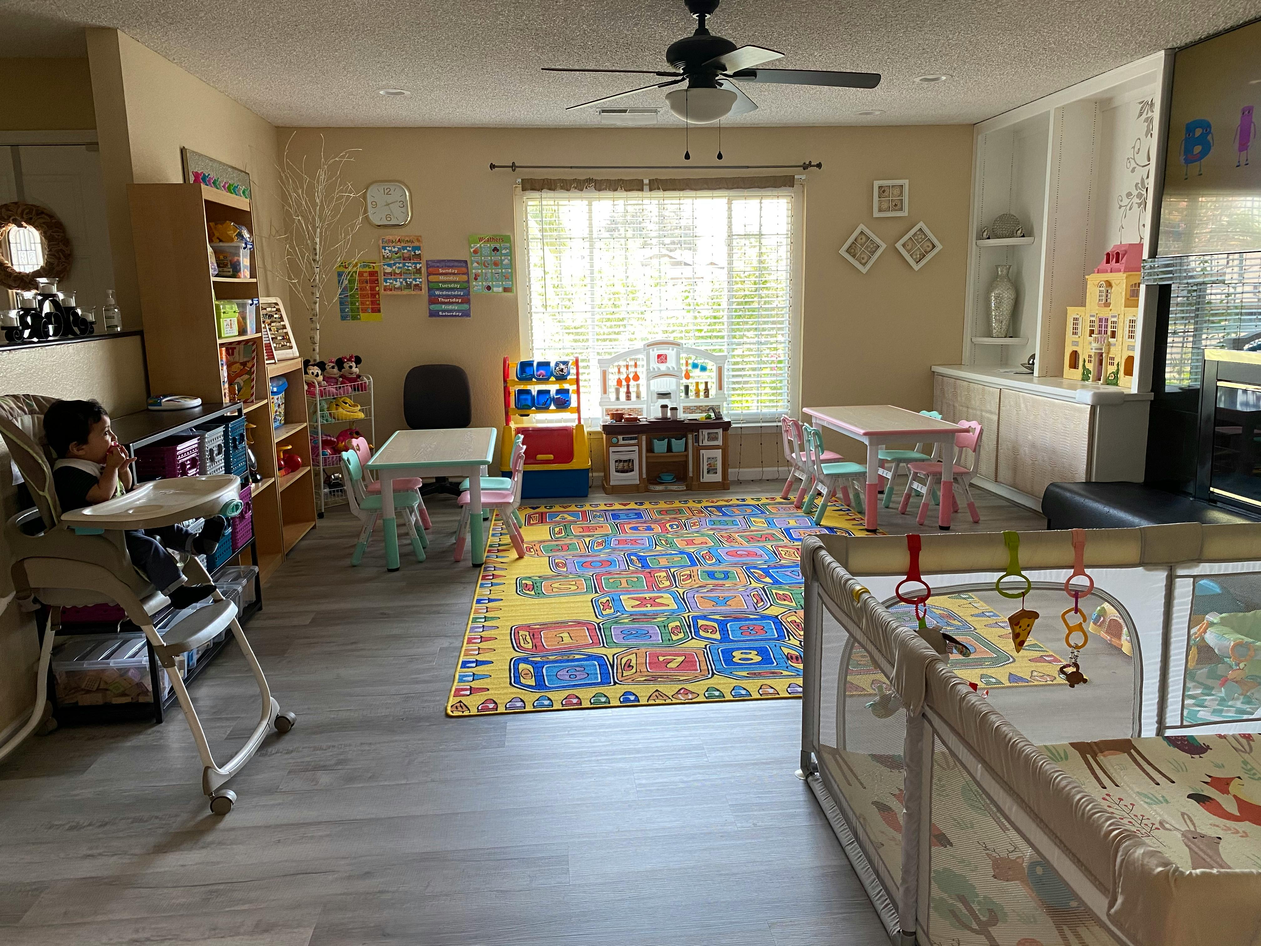 Child in a high chair in a playroom with toys and furniture