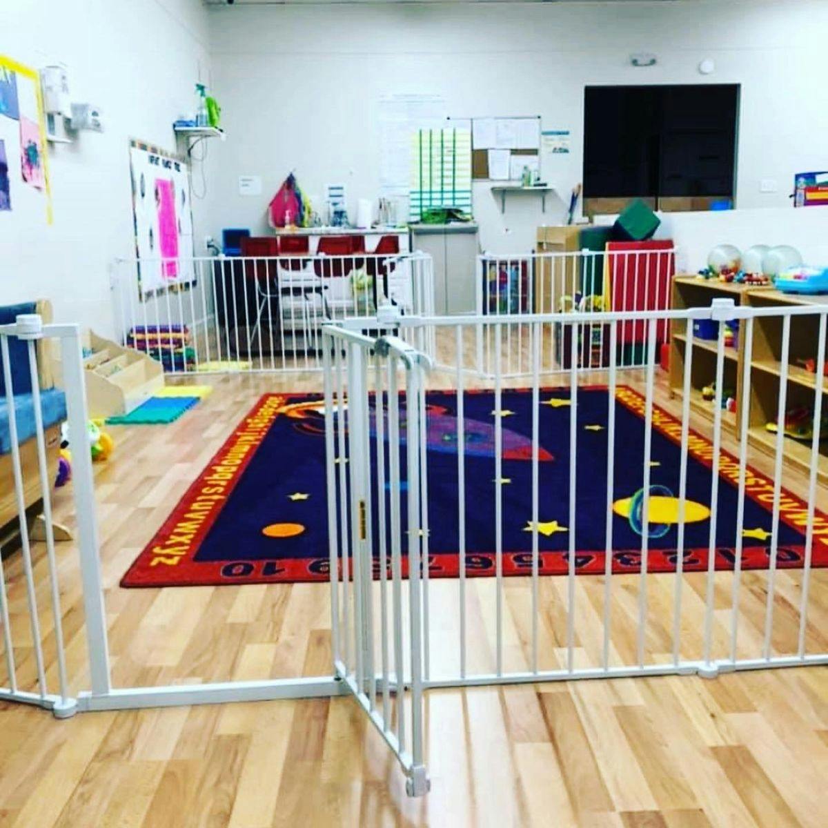 Playroom with a space-themed rug and white safety gates