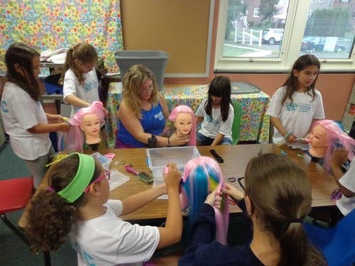Adult and children styling mannequin heads with colorful hair