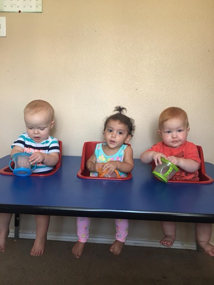 Three children sitting at a table with cups