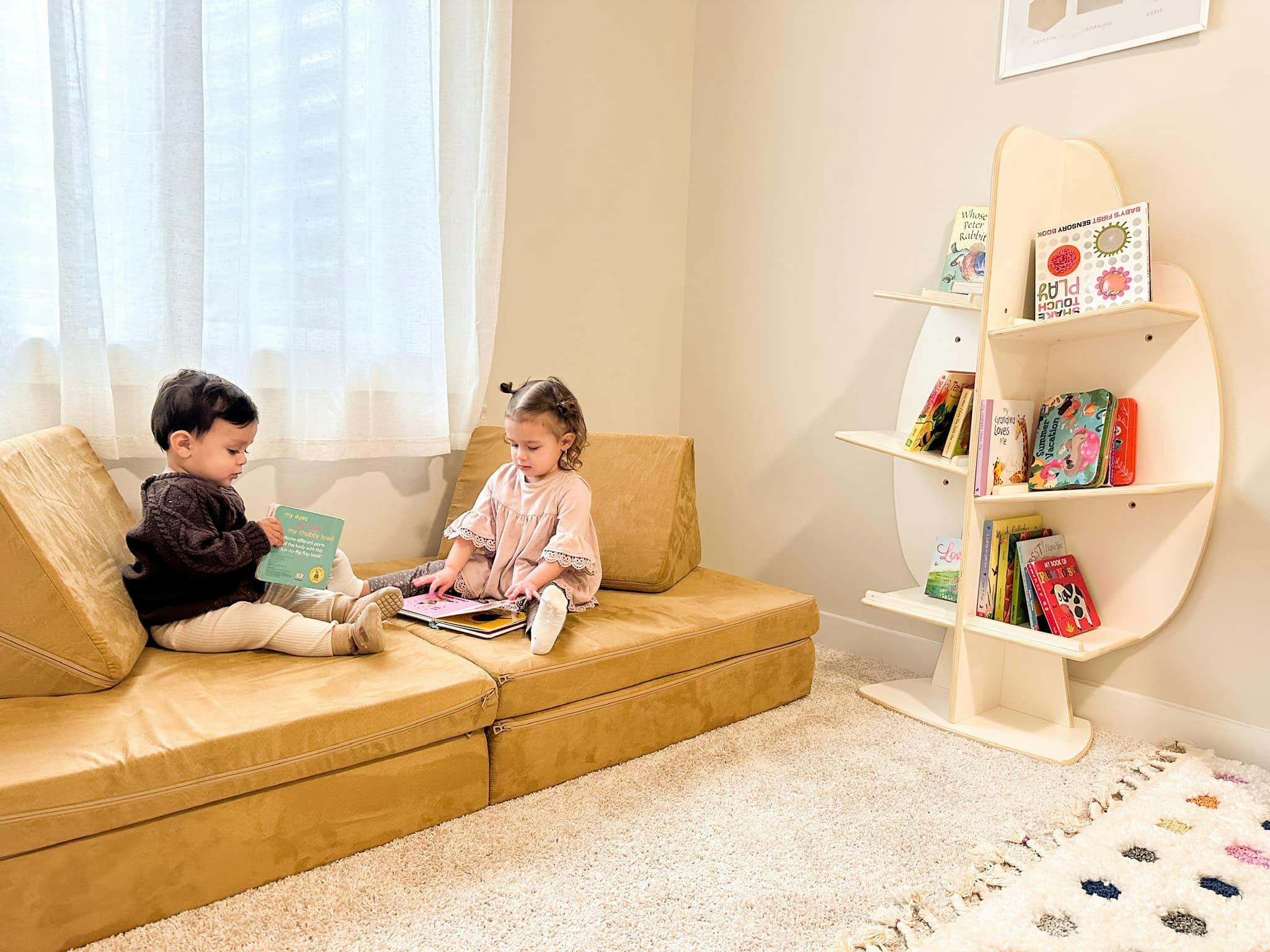 Two children sitting on a sofa reading books