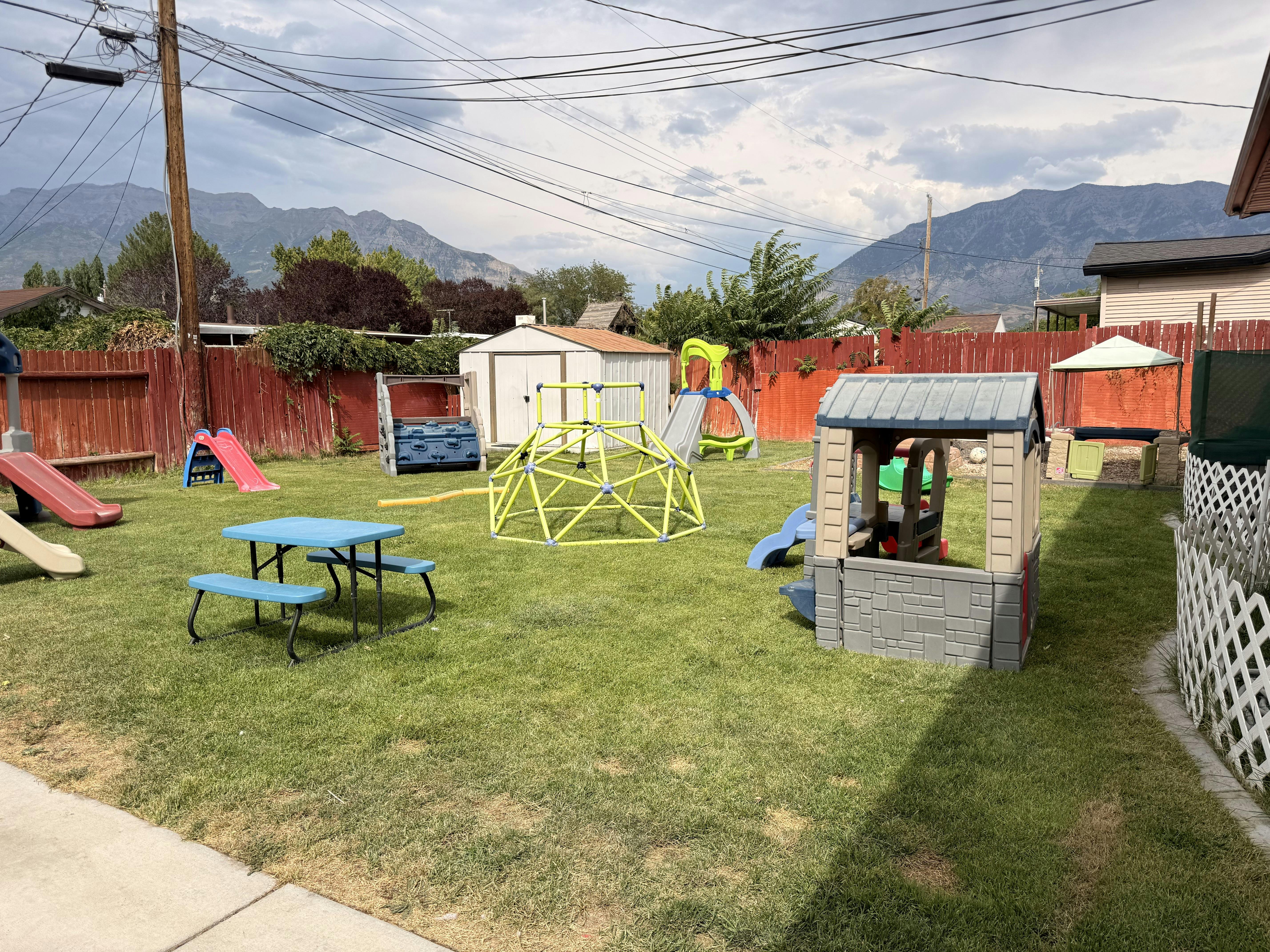 Backyard playground with climbing equipment, slides, and a playhouse