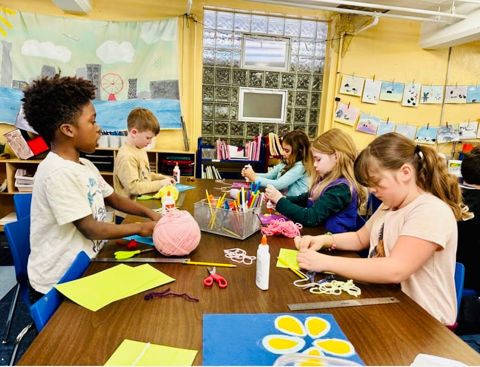 Children doing crafts at a table in a classroom