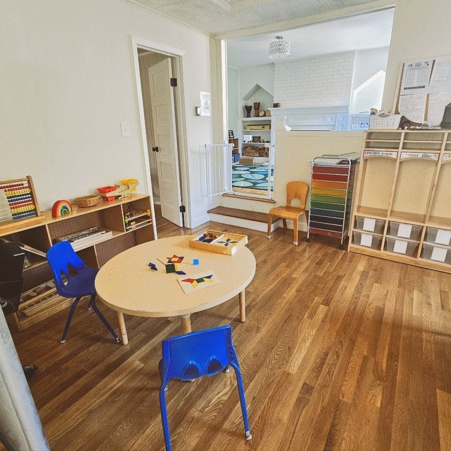 Classroom with a table, chairs, and shelves with learning materials