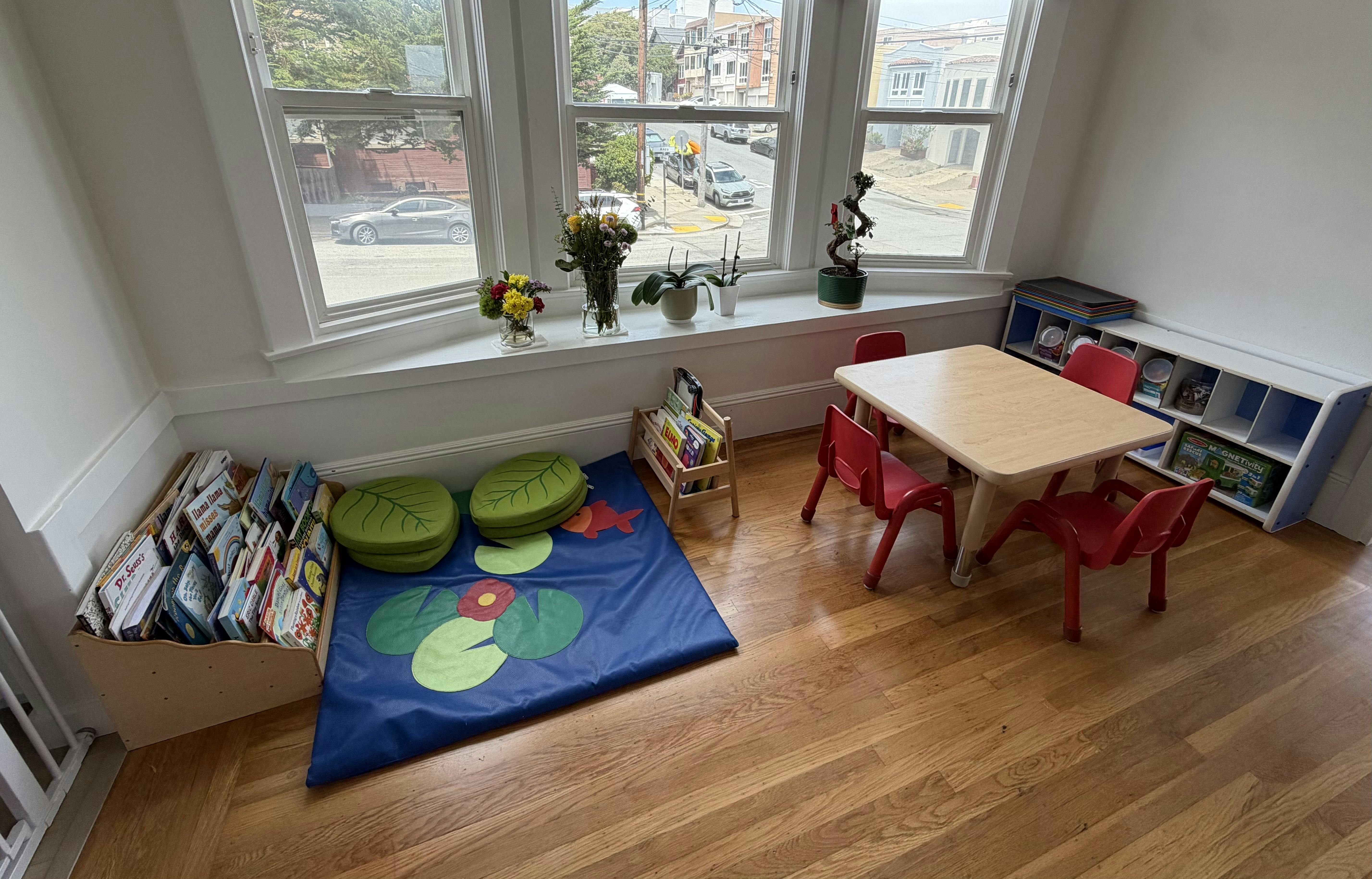 Play area with children's table chairs books and a floor mat