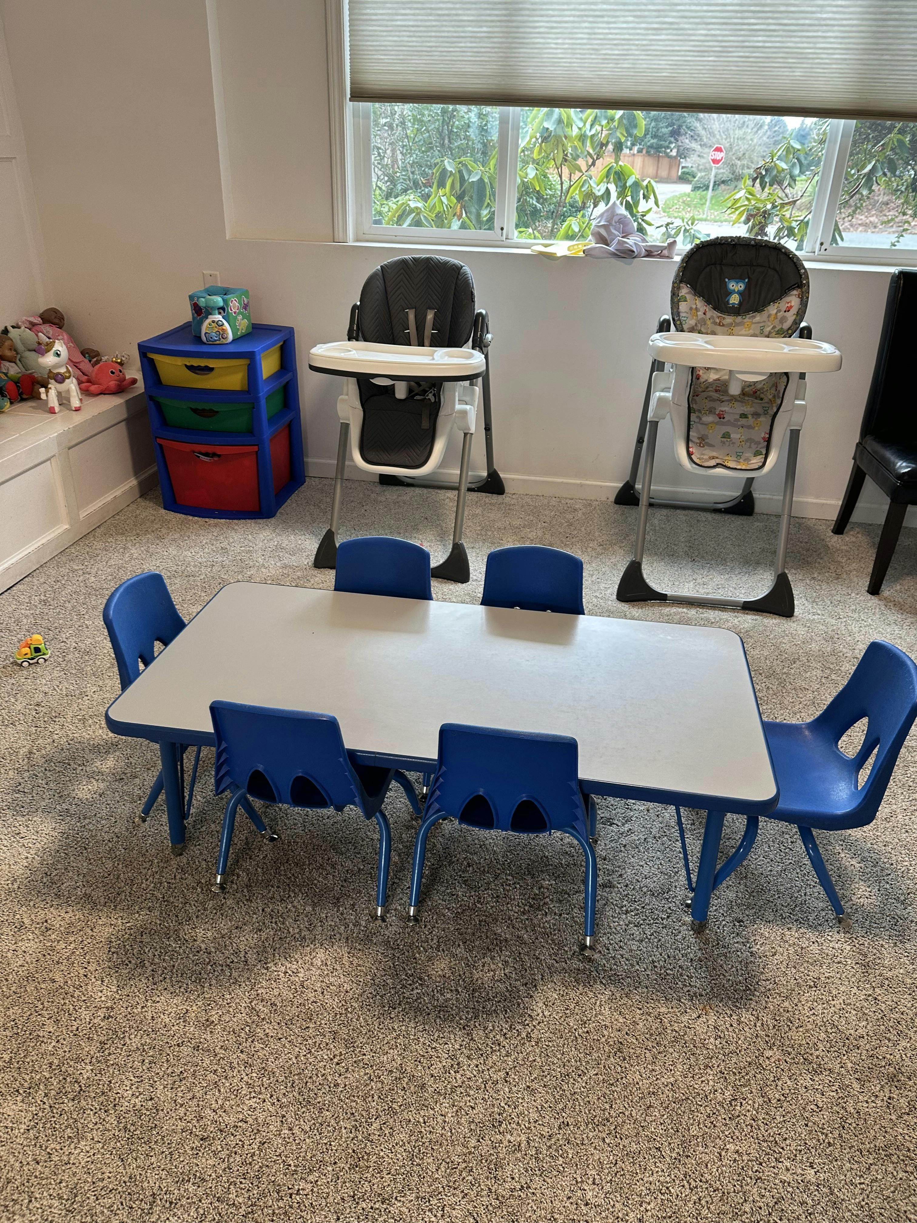 Children's table with blue chairs and two high chairs in a room