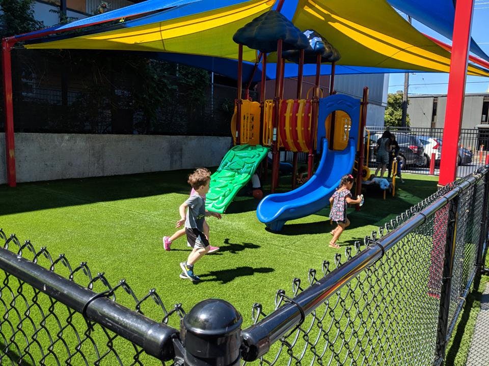 Two children running on artificial grass in a playground