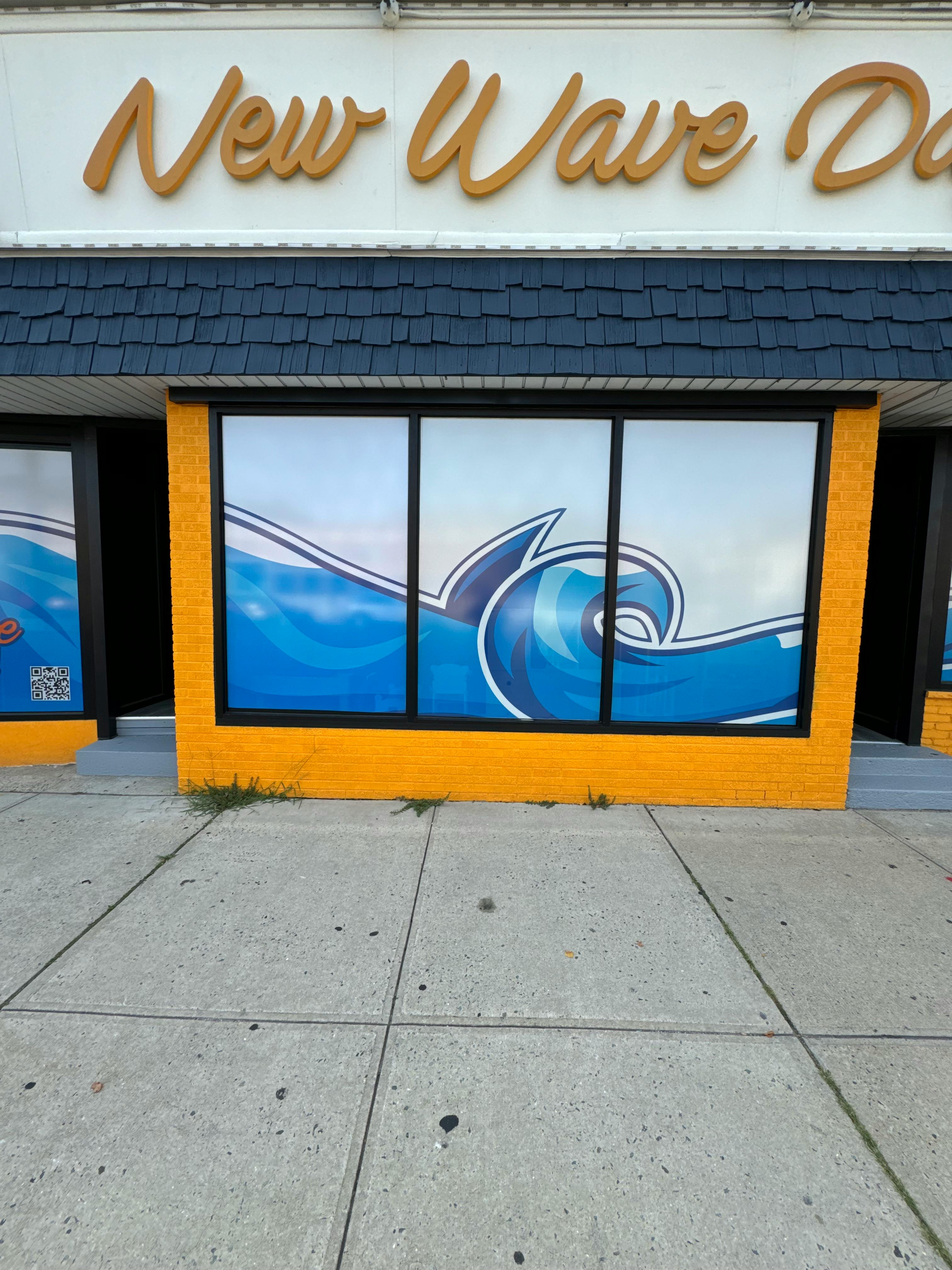 Storefront with "New Wave" sign and window decals of blue waves