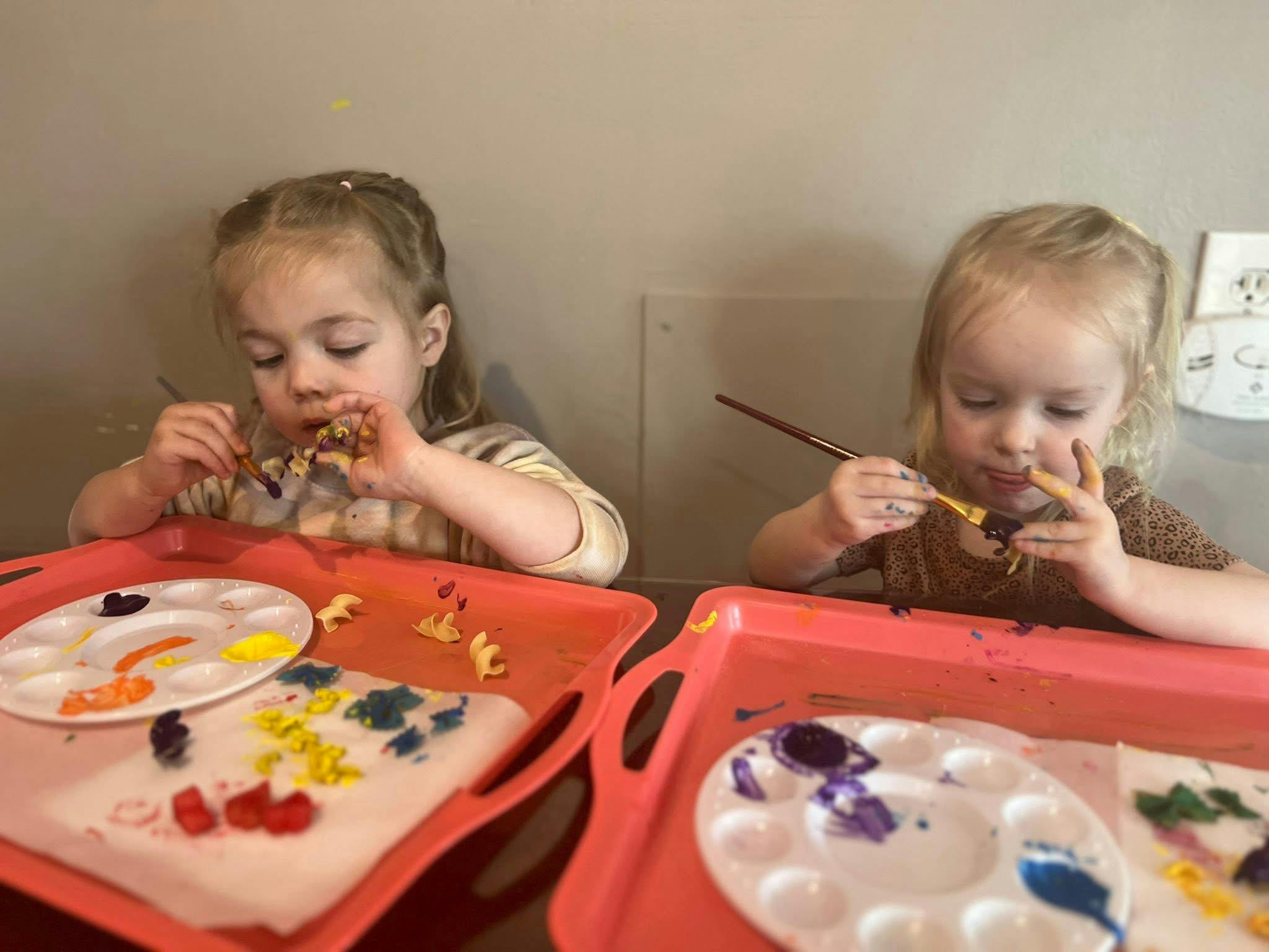 Two children painting with brushes and paint palettes