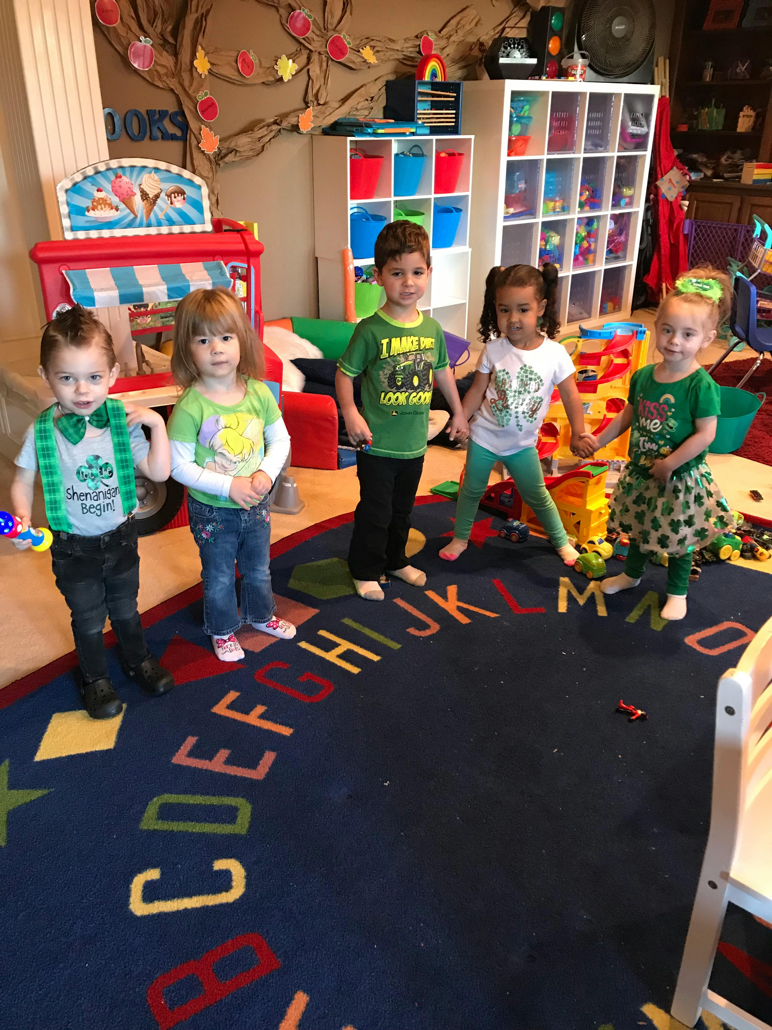 Five children standing and looking at the camera in a playroom