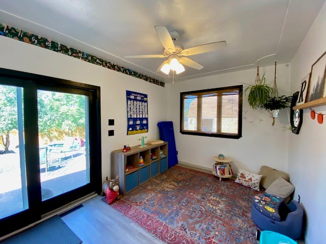 Room with a patterned rug, sliding glass door, and ceiling fan