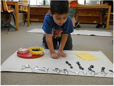 Child on floor playing with small objects and toy airplanes